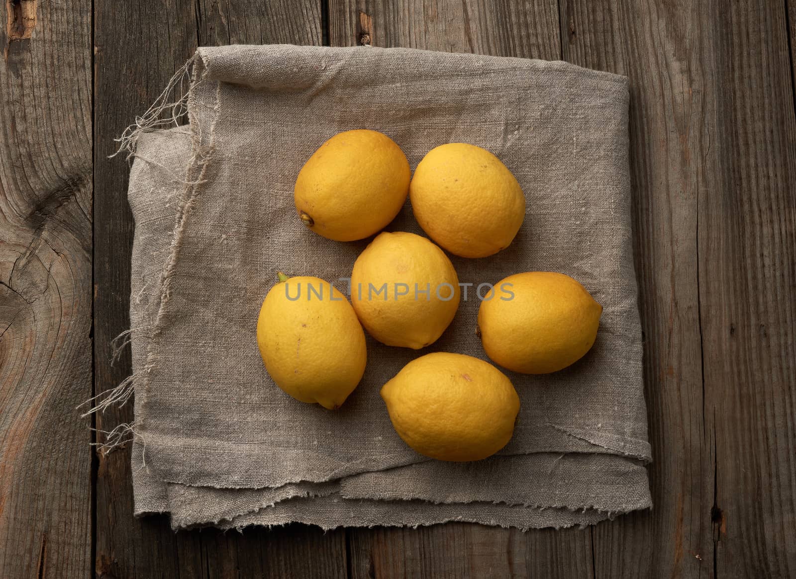 yellow round lemons on a gray textile napkin, top view