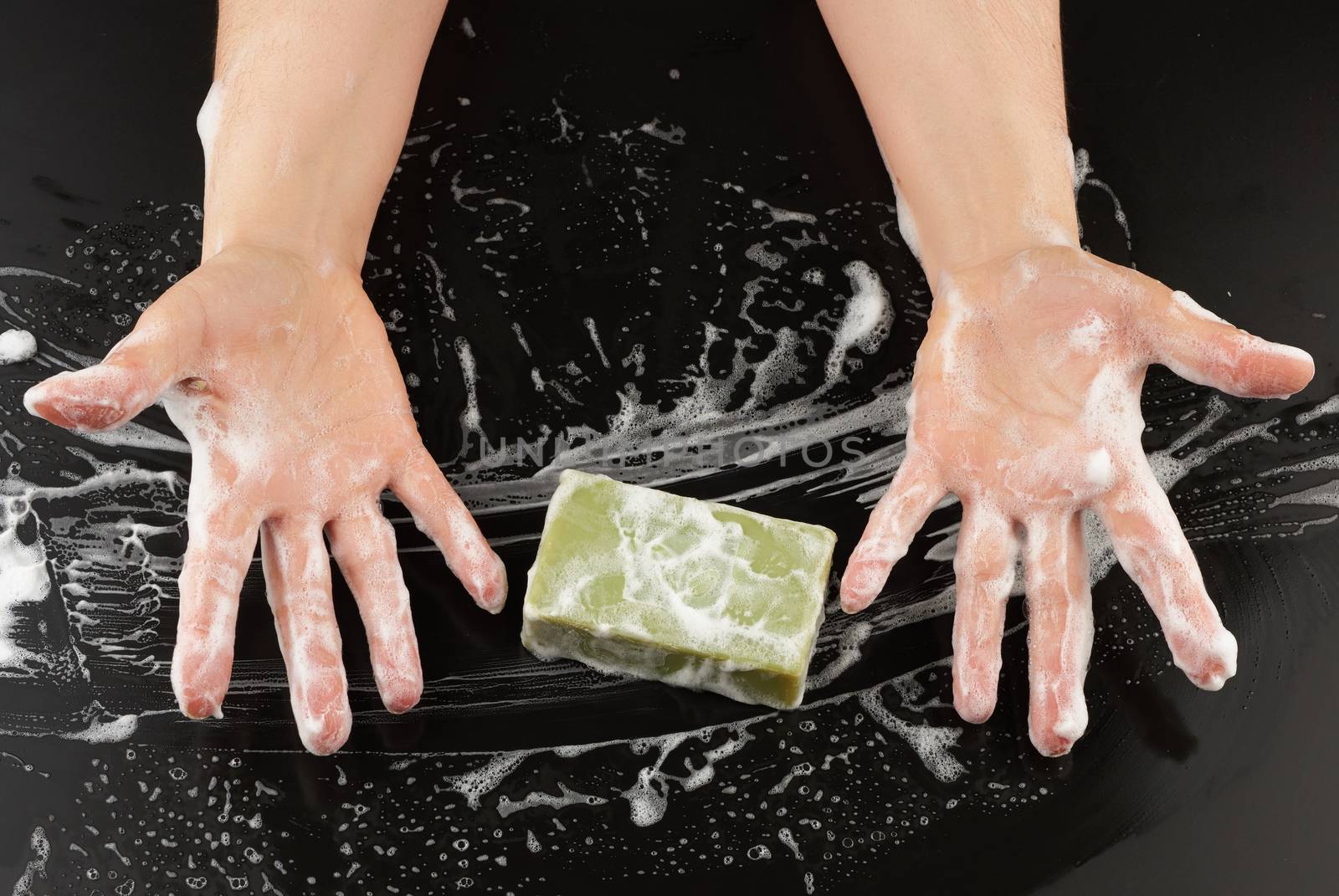 process of washing hands with blue soap, parts of the body in white foam on a black background, top view, hygiene concept
