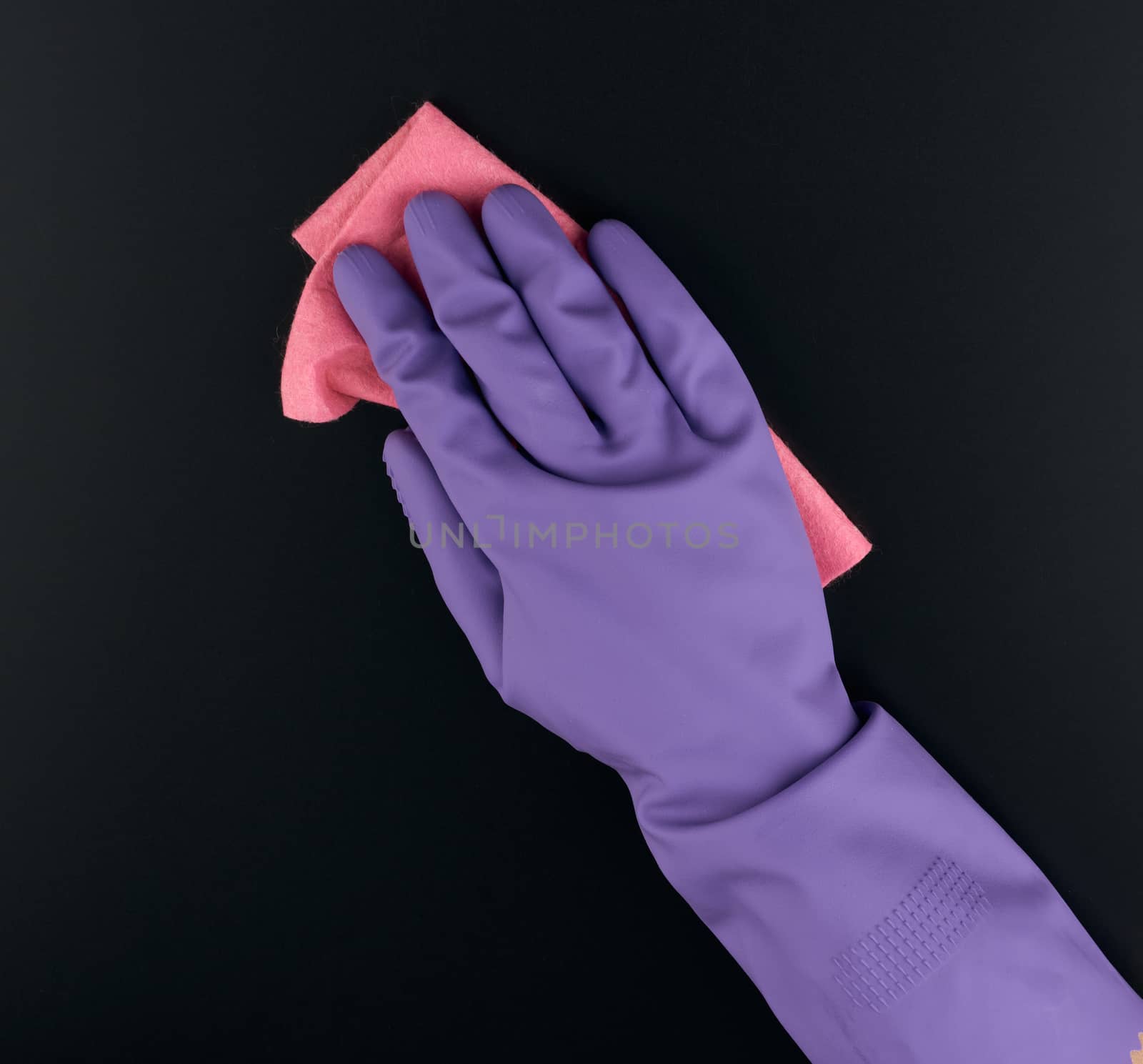hand holds a pink rag sponge for cleaning, protective purple rubber glove is worn on the arm,  close up