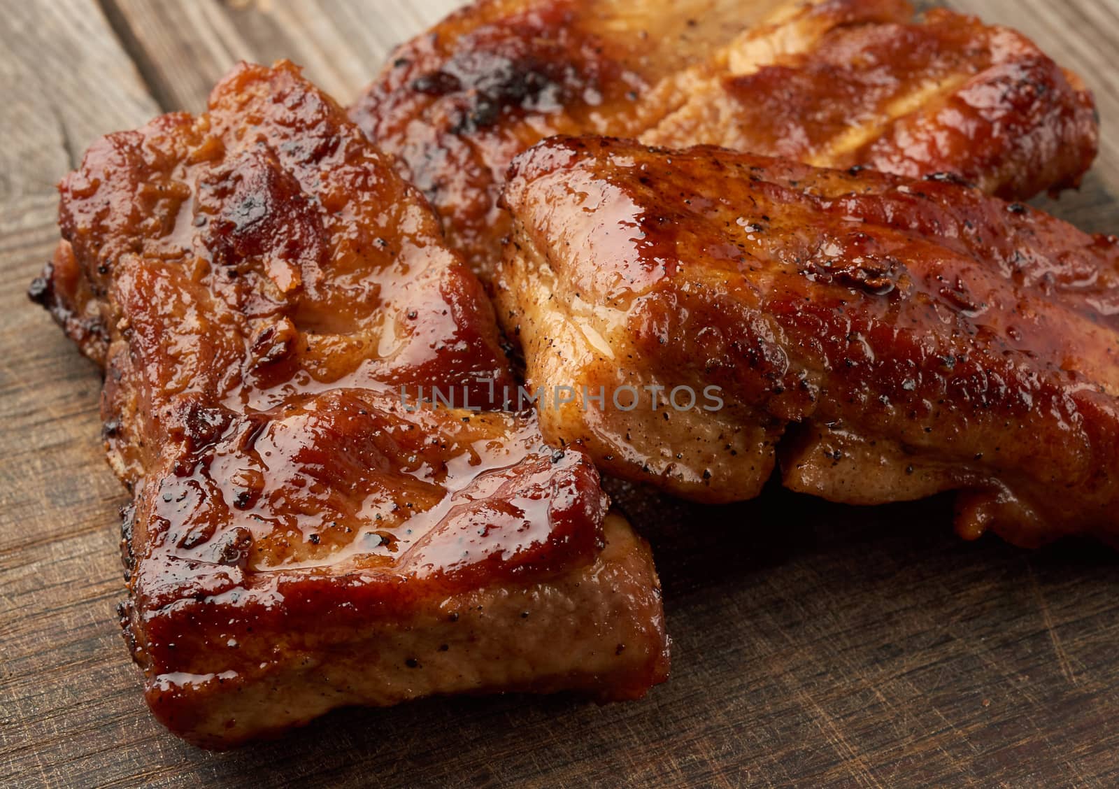 fried pork ribs on a brown wooden board, close up