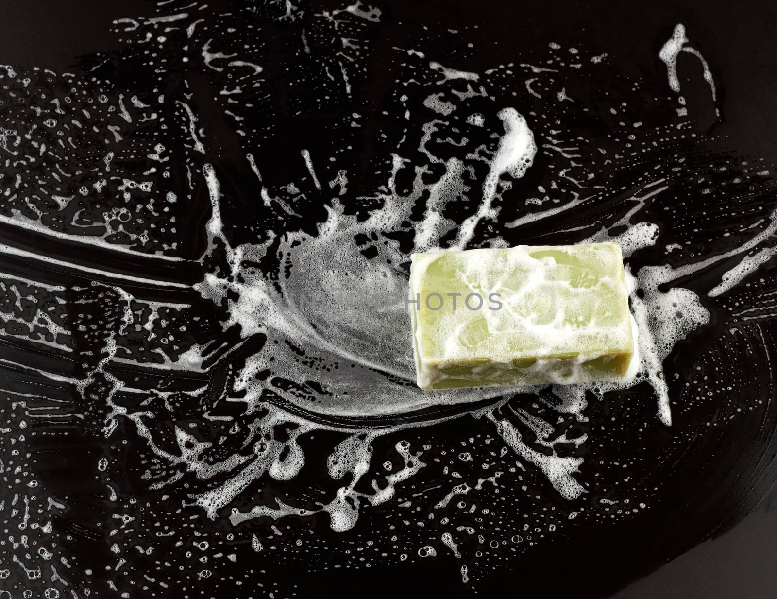 white soap foam and green soap on a black background, top view, concept of cleanliness, antibacterial
