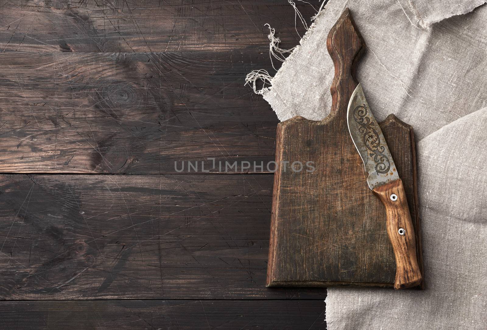empty old wooden cutting board and vintage knife on the table, top view