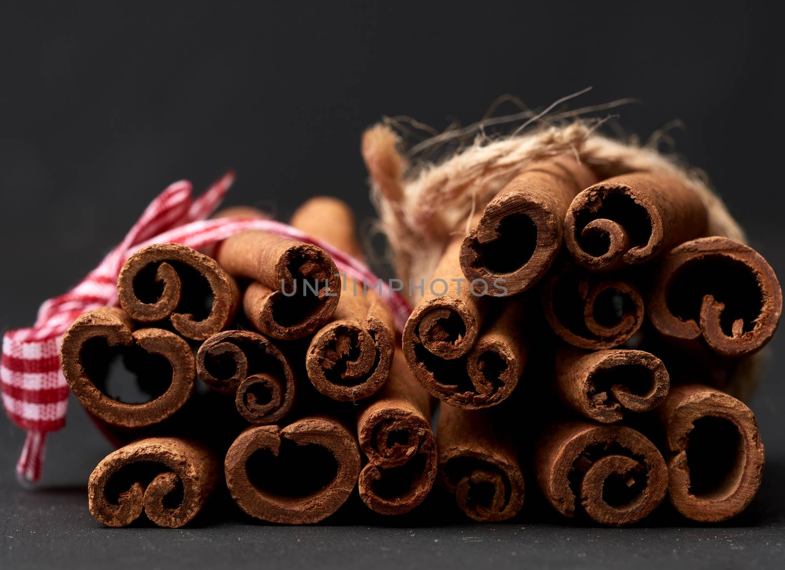 tied bunch of brown cinnamon sticks on a dark background, close up