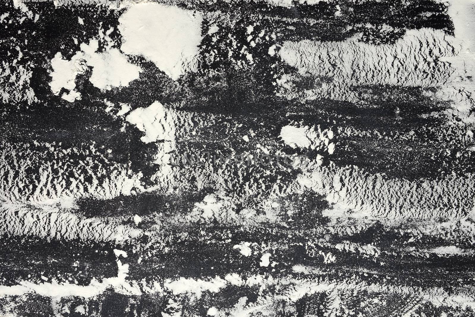 white wheat flour scattered on a black table, top view
