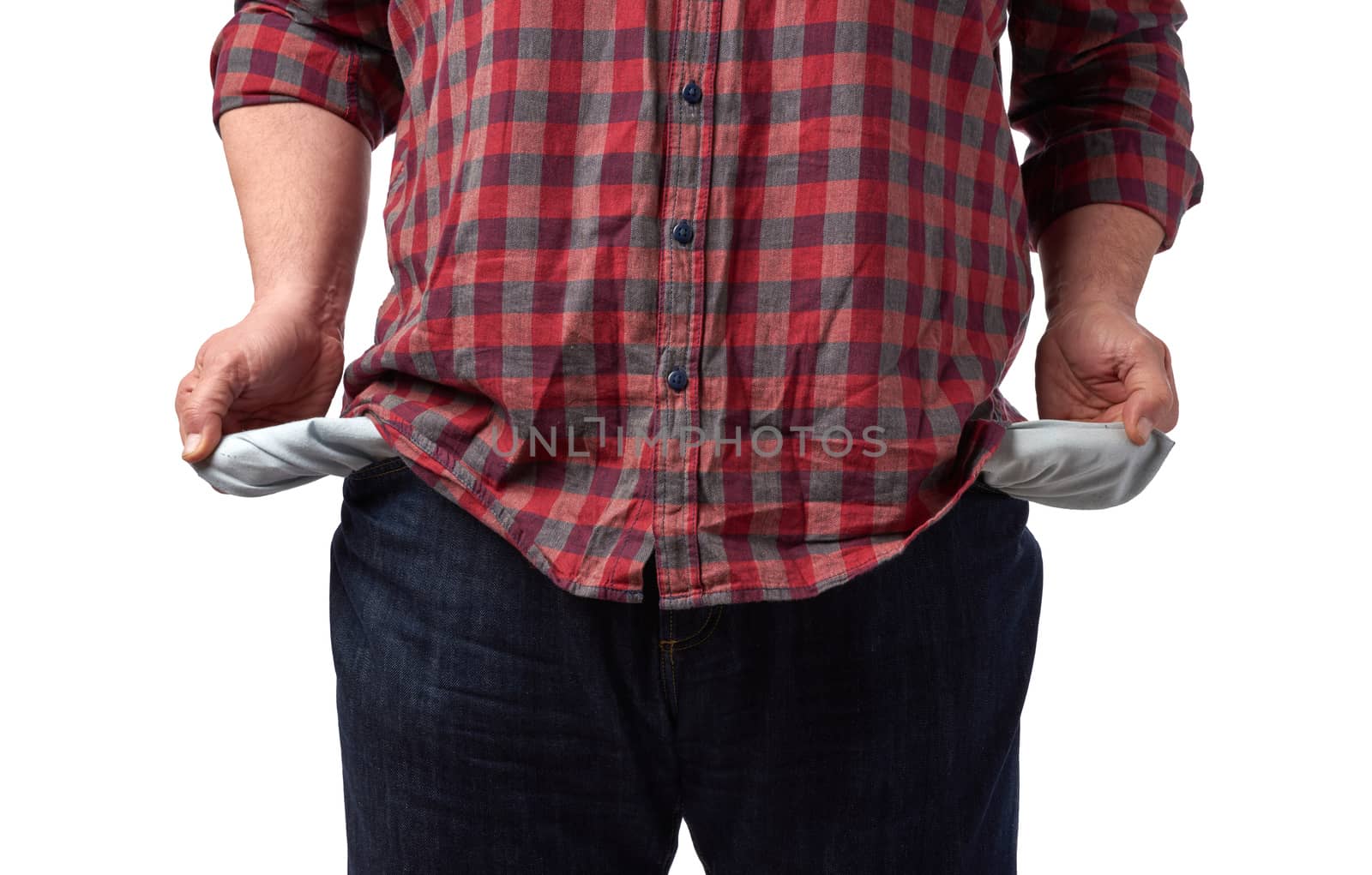 man in a red shirt turned out the empty pockets of his pants, concept of poverty and crisis, unemployment, close up, while background 