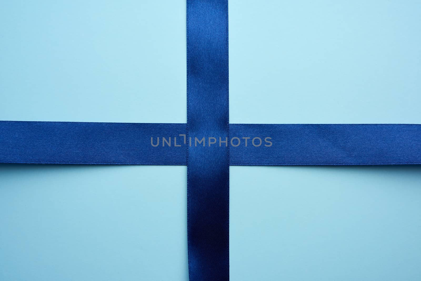 blue silk ribbon crossed on a blue background, imitation of tying a gift, top view
