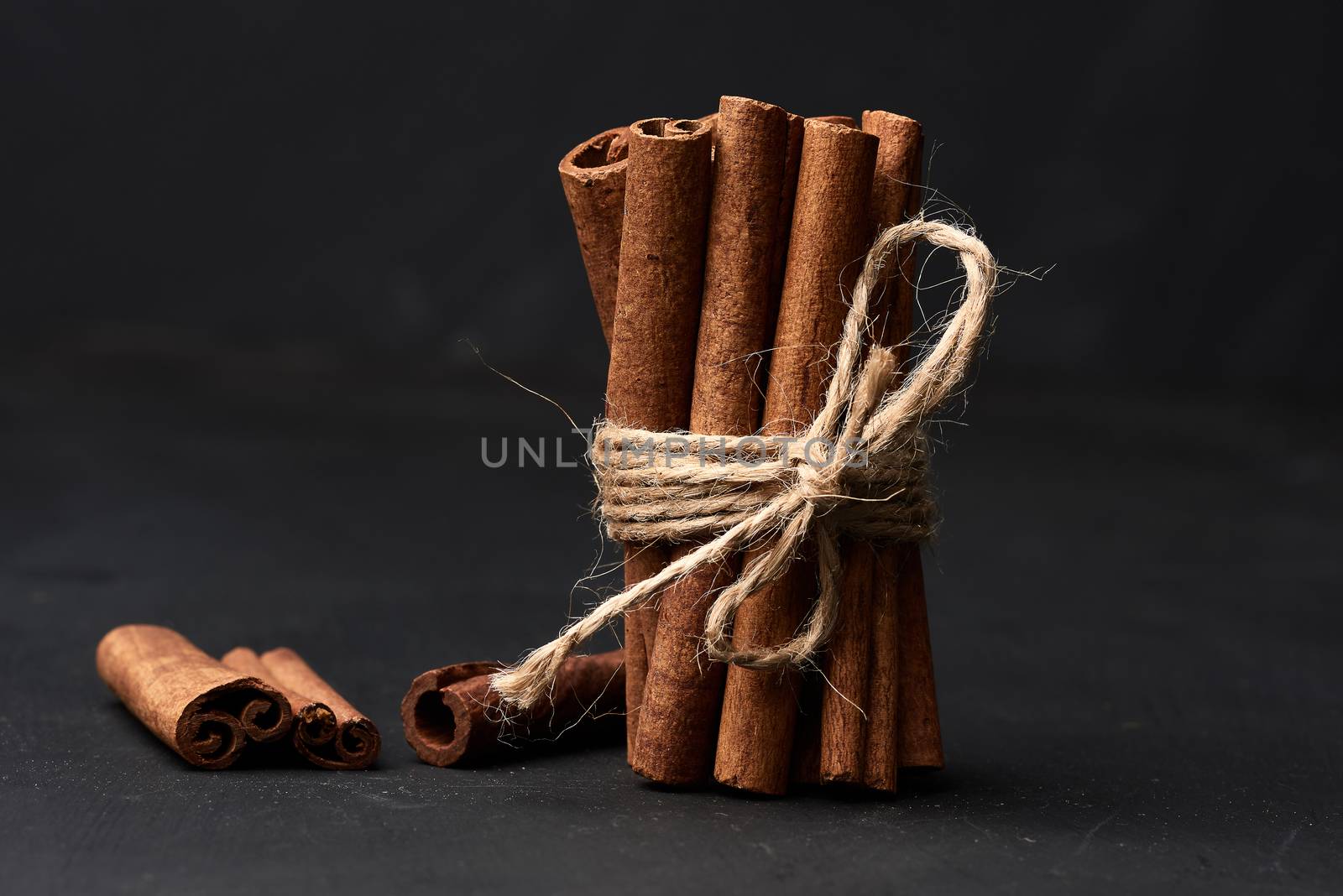 tied bunch of brown cinnamon sticks on a dark background, close up