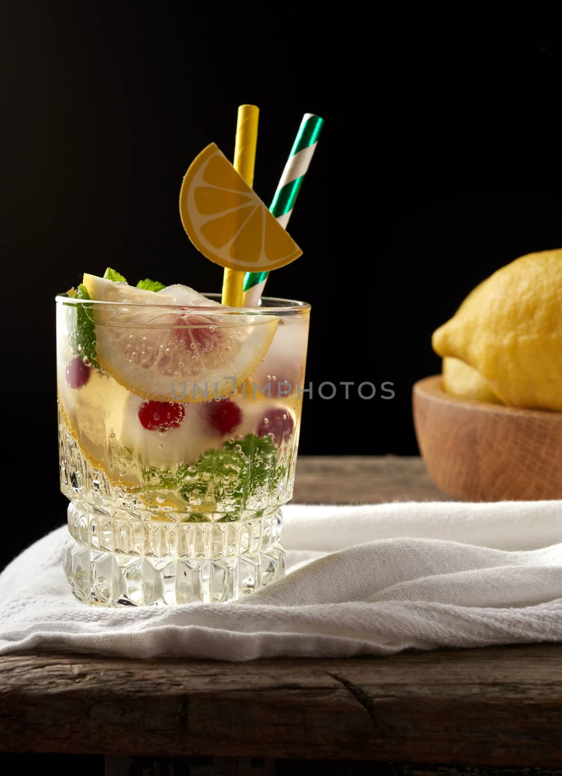 transparent glass with lemonade and pieces of ice, red berries, a refreshing summer drink, close up