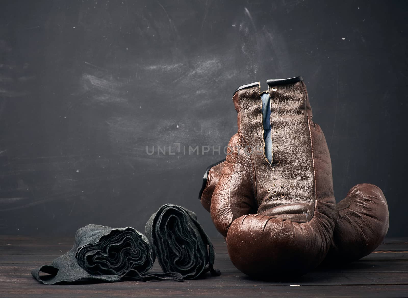 brown leather vintage boxing gloves and black elastic bandage for hands on a black background, sports equipment