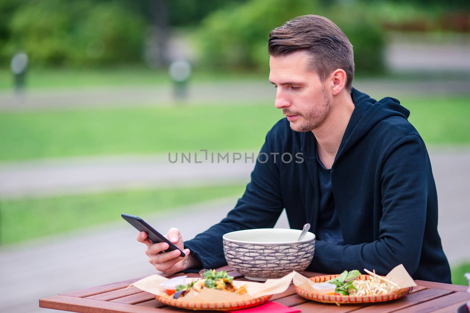 Young man eating take away noodles on the street by travnikovstudio