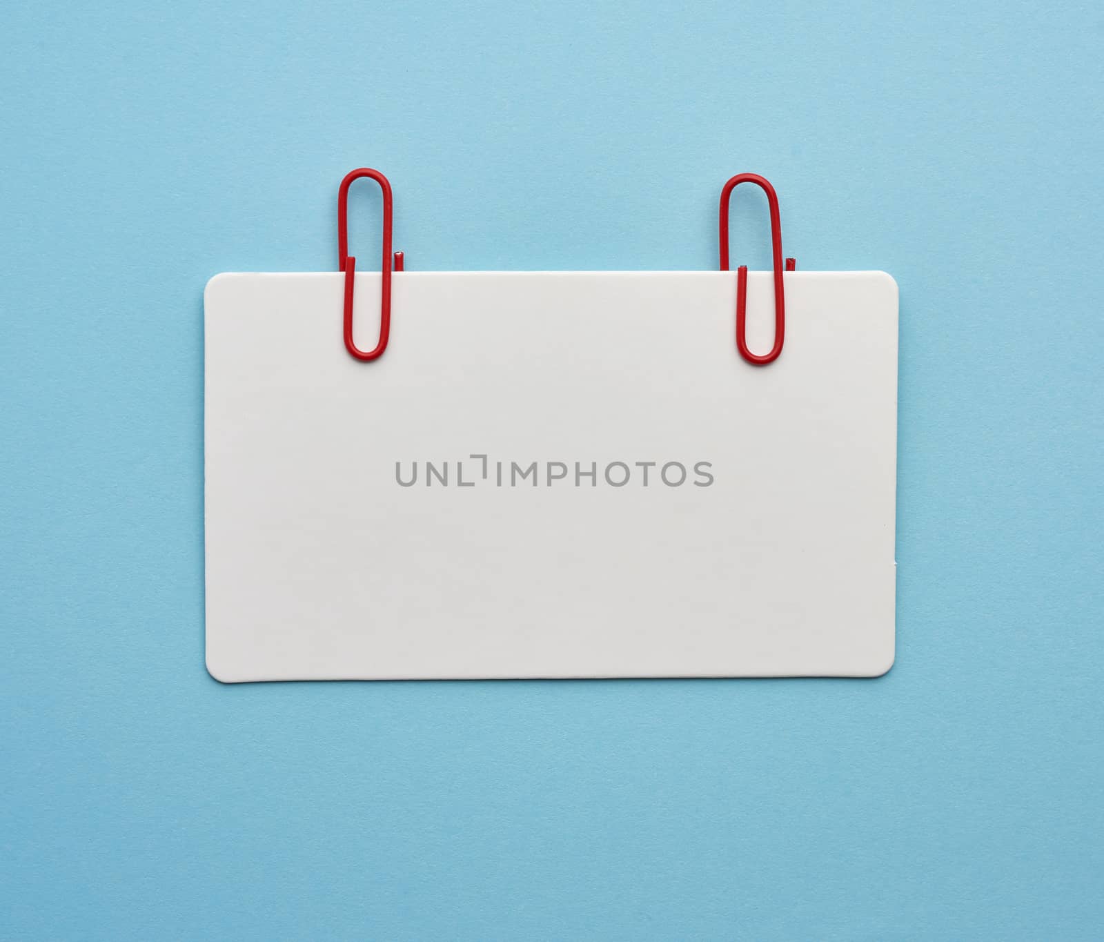 rectangular white paper blank business card on a blue background, top view