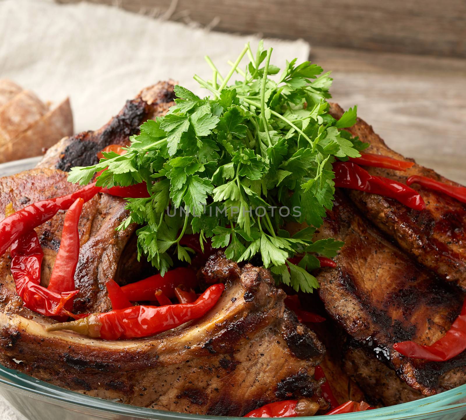 grilled pork steaks on the bone lie in a transparent glass plate on a wooden table, barbecue