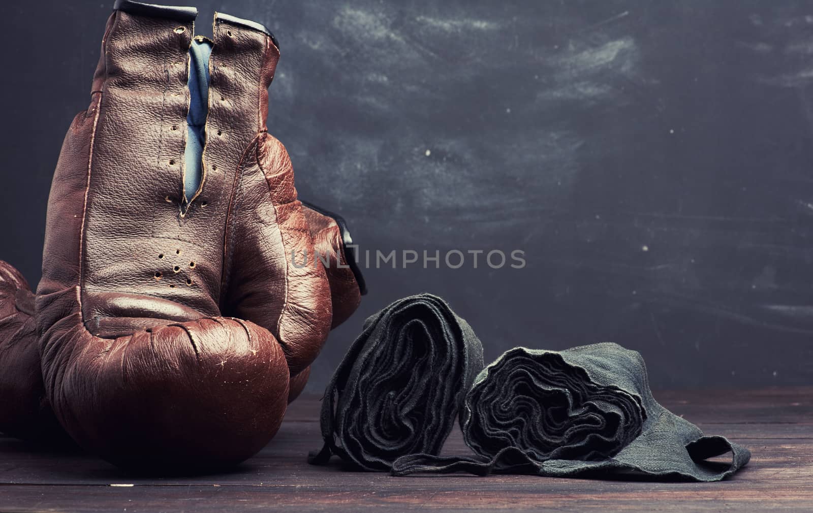 brown leather vintage boxing gloves and black elastic bandage for hands on a black background, sports equipment