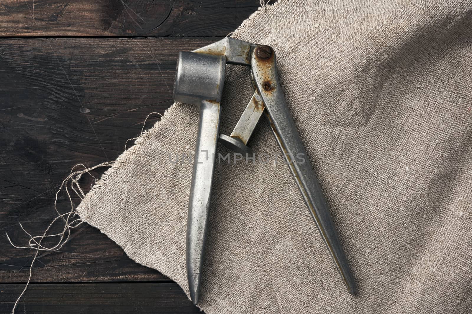 old metal press for garlic and other spices on a brown wooden table, top view