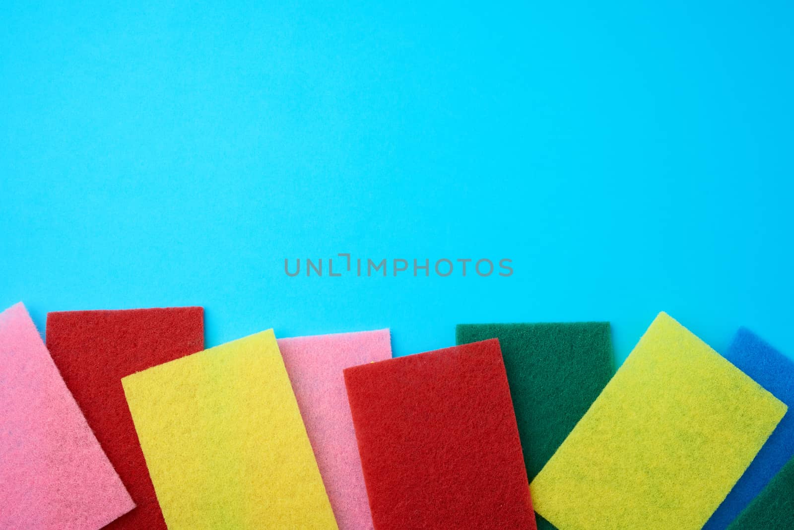new multi-colored kitchen sponges for washing dishes on a blue background, flat lay, copy space