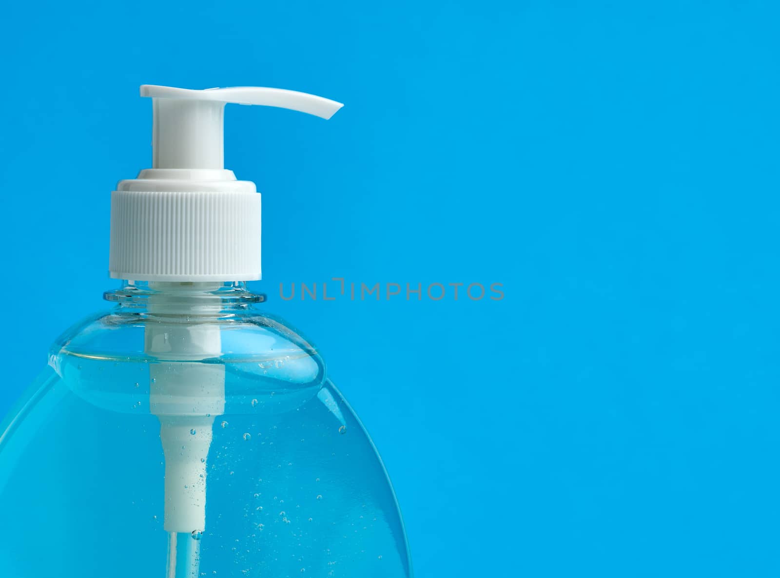 transparent plastic bottle with a sanitizer for disinfecting hands on a blue background, a place for inscription