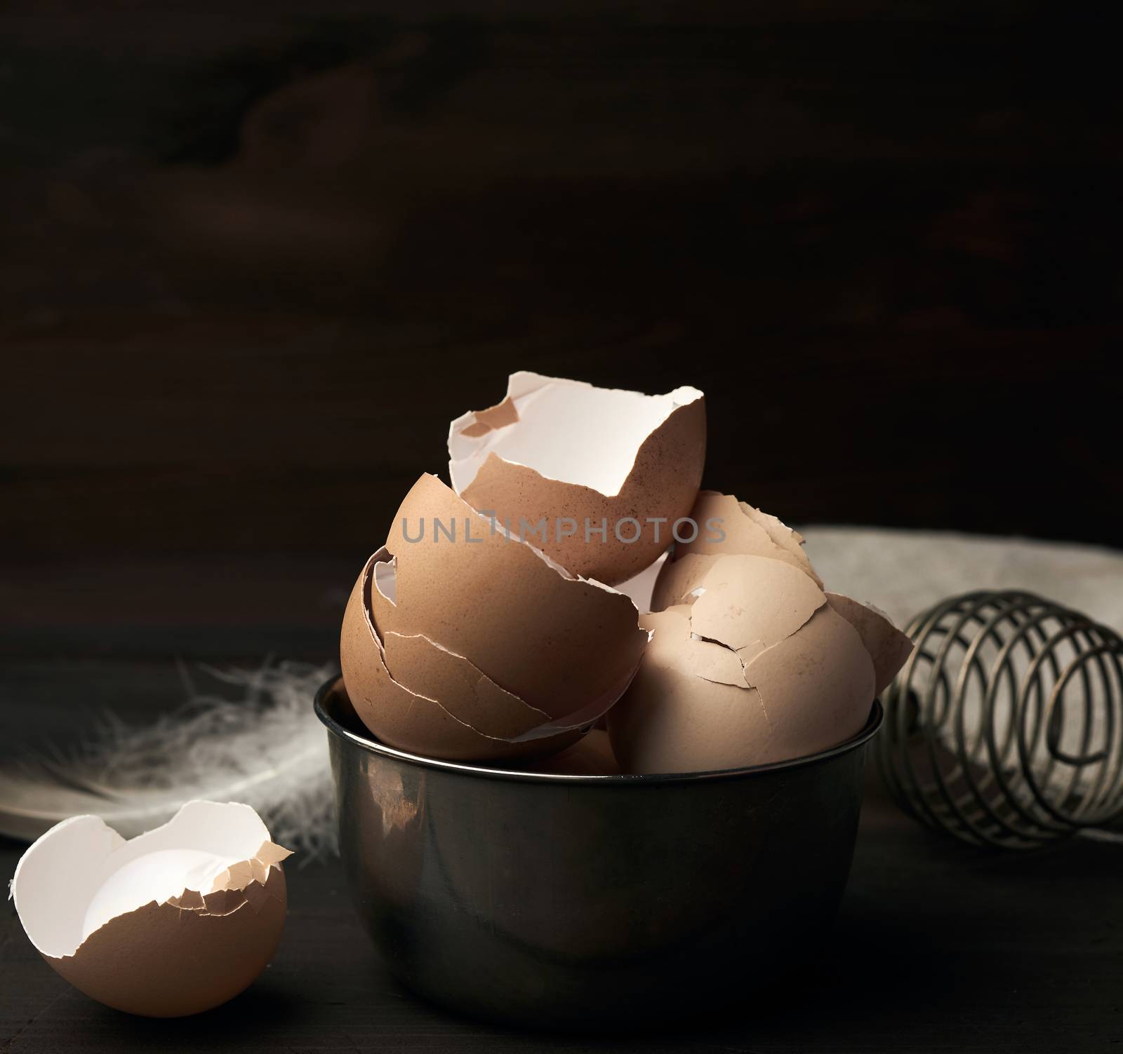 brown raw chicken shell in an iron bowl on a wooden table, close up