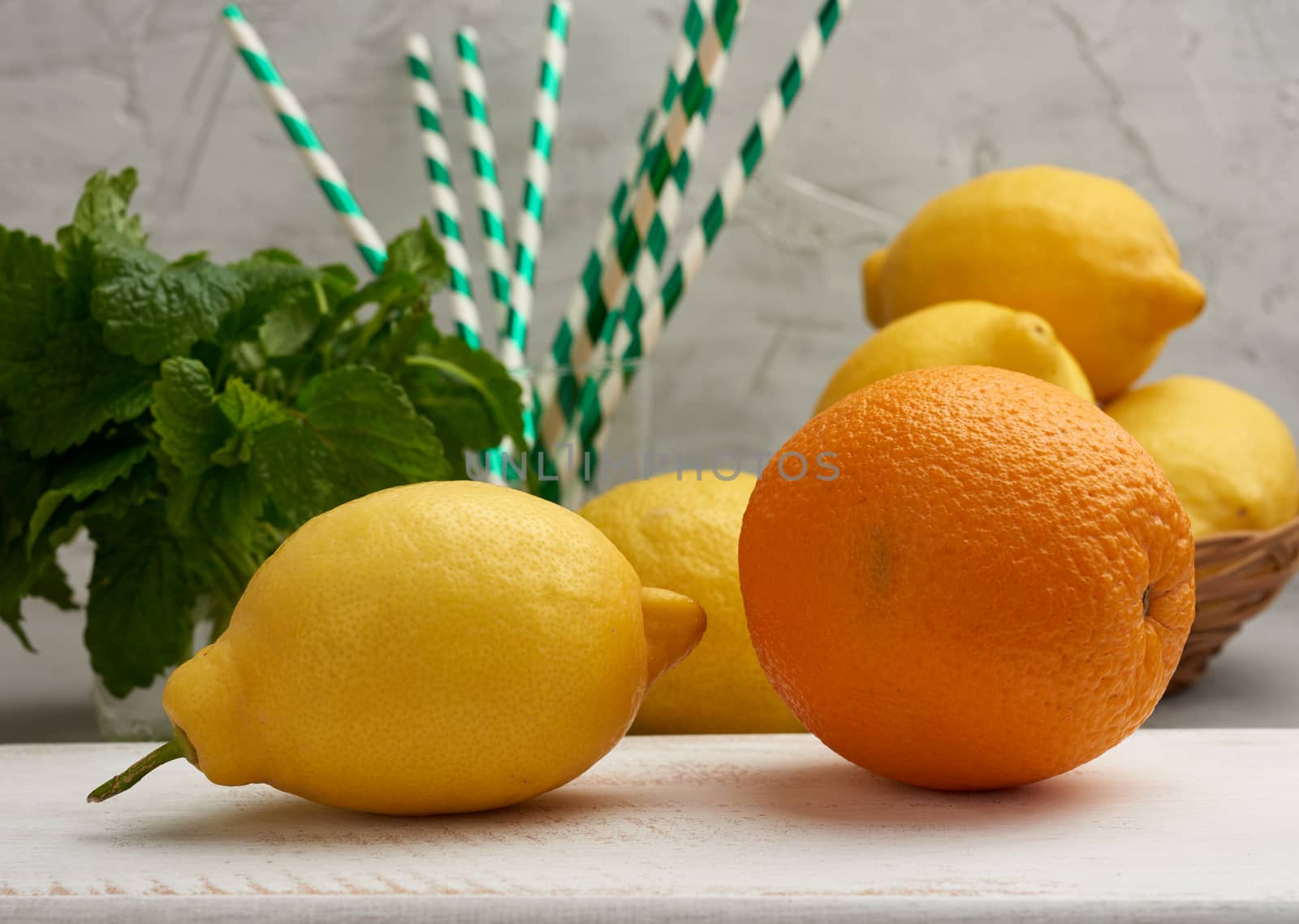 whole orange, yellow ripe lemon and a bunch of mint on a wooden board, ingredients for lemonade