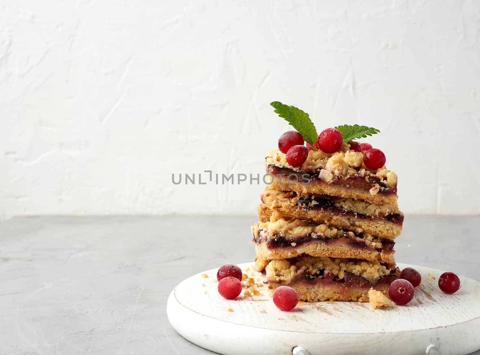 stack of square slices of baked crumble pie with blue plum on a white wooden board, delicious dessert, copy space