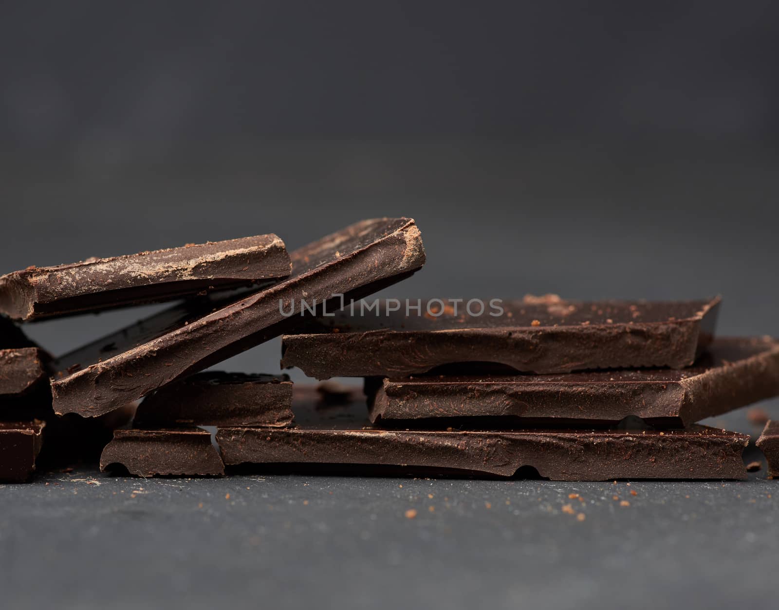 pieces of black chocolate on a black background, sweet dessert, close up