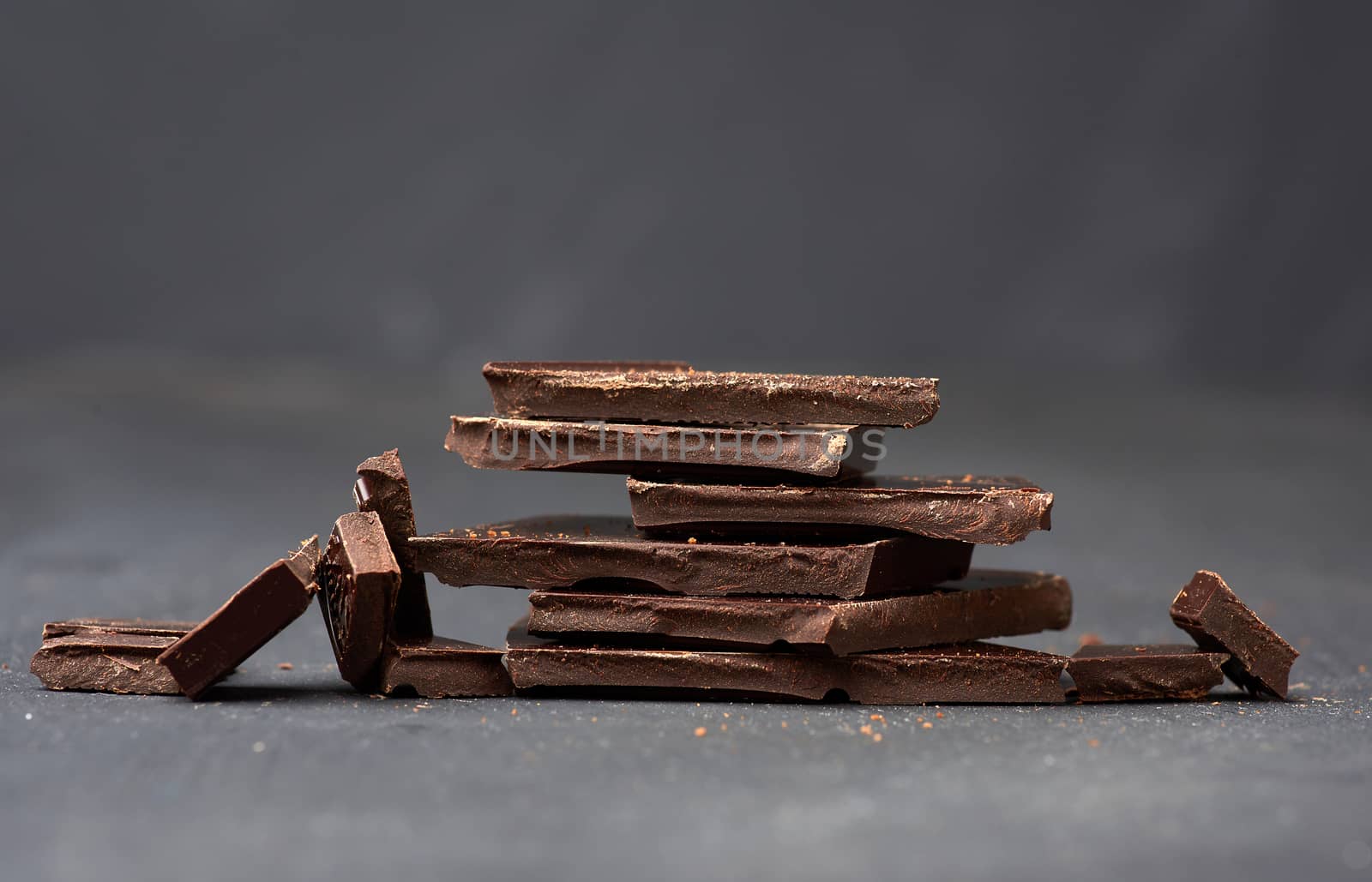 pieces of black chocolate on a black background, sweet dessert, close up