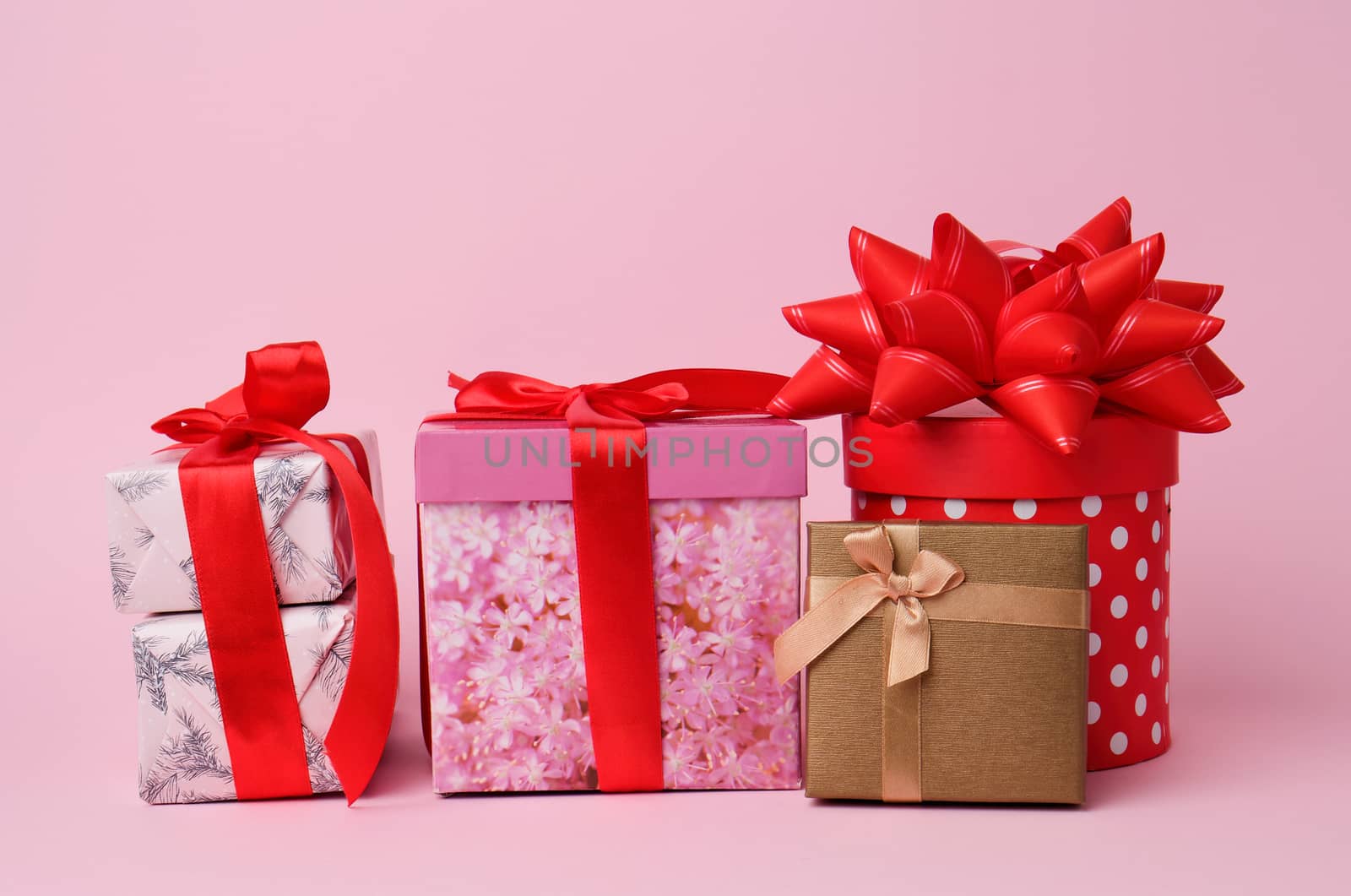 stack of wrapped gifts with knotted bows on a pink background, festive backdrop