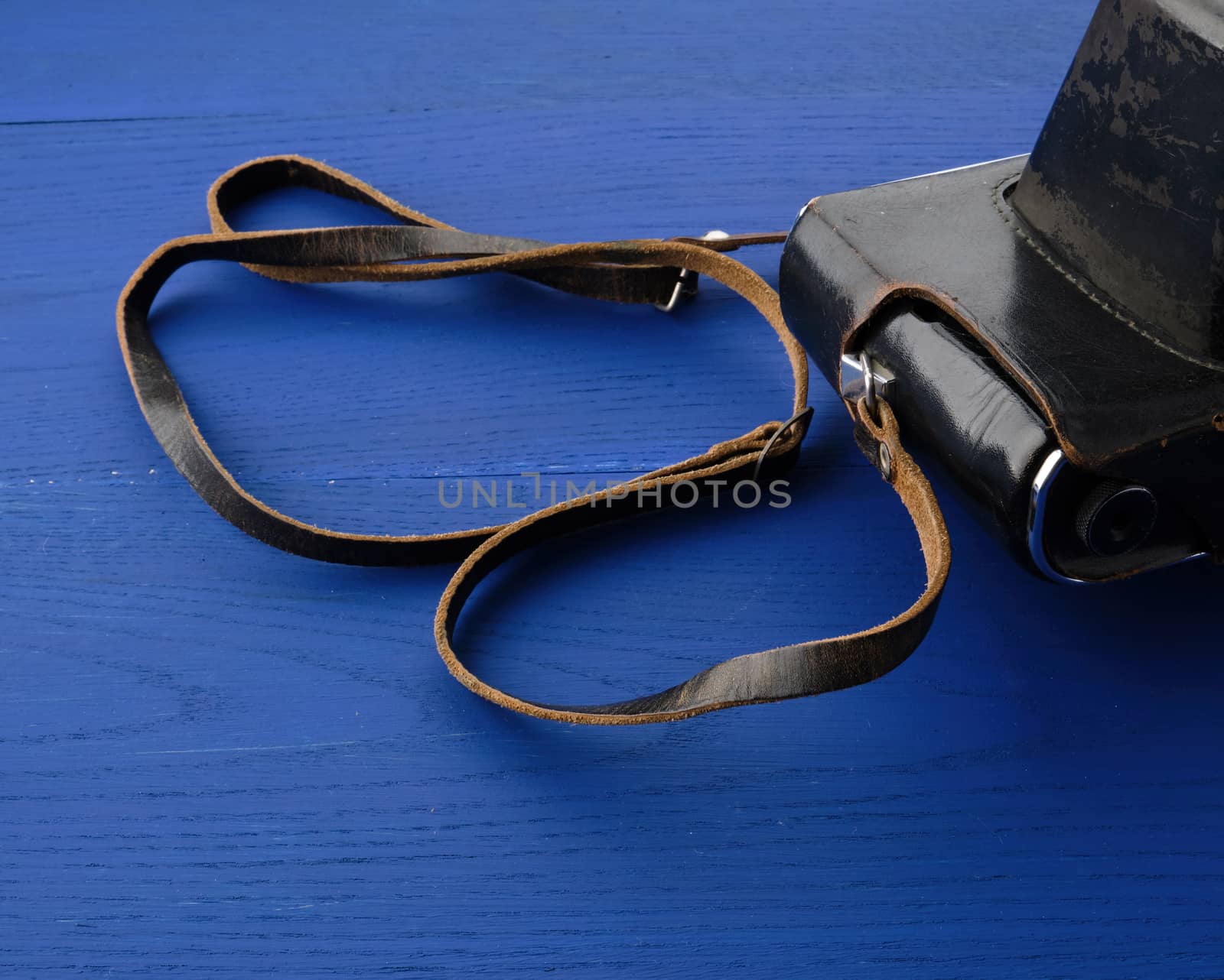Vintage film camera in a leather case on a wooden blue background, close up