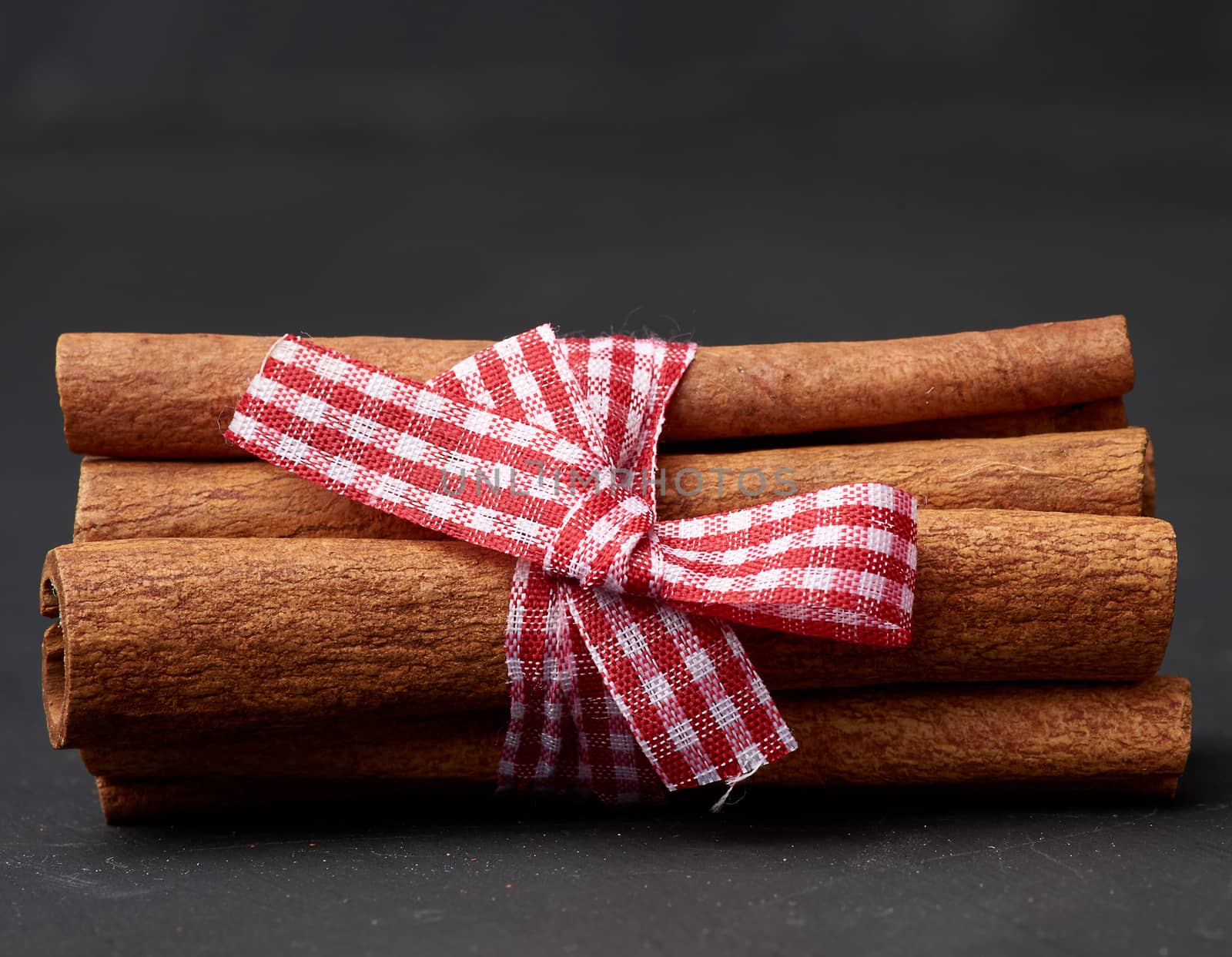 tied bunch of brown cinnamon sticks on a dark background, close up