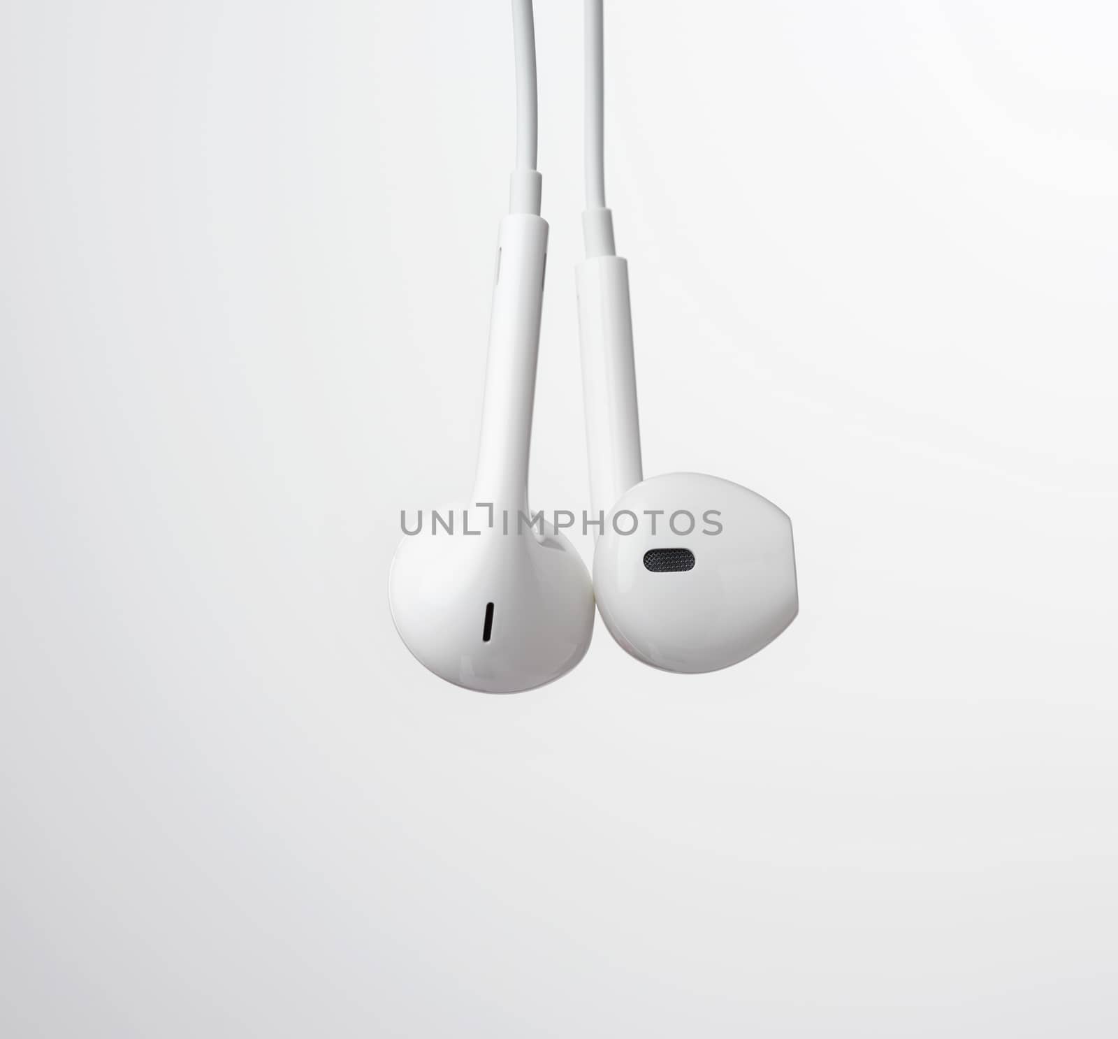 hanging headphones on a white cable, modern gadget on a white background, close up
