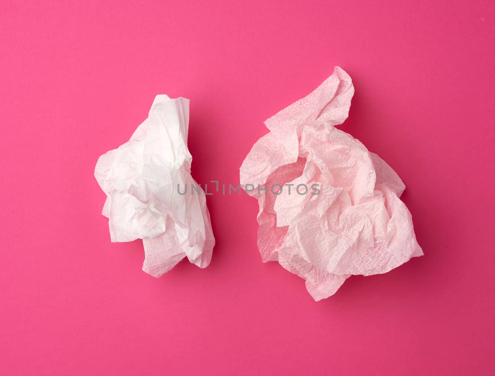 crumpled white paper disposable napkins on a pink background, top view