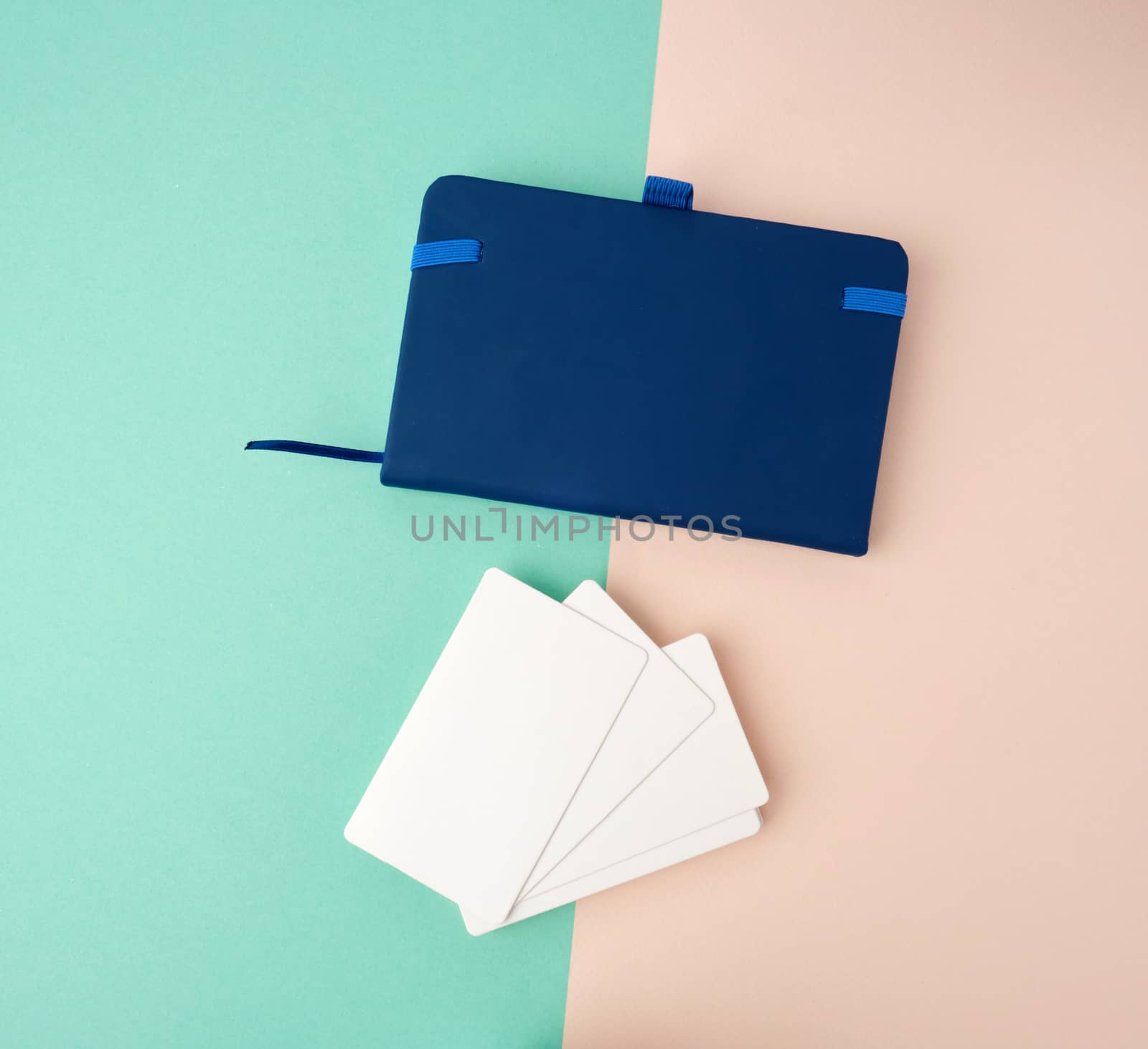 stack of rectangular white blank business cards and blue notebook on a green beige background, backdrop for the designer