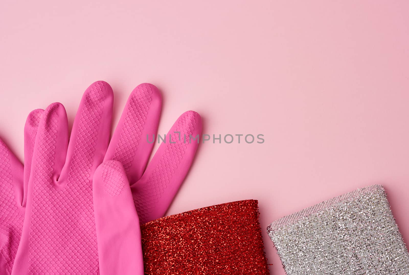 multi-colored kitchen sponge, rubber pink gloves on a pink background, set of items for cleaning, top view, copy space