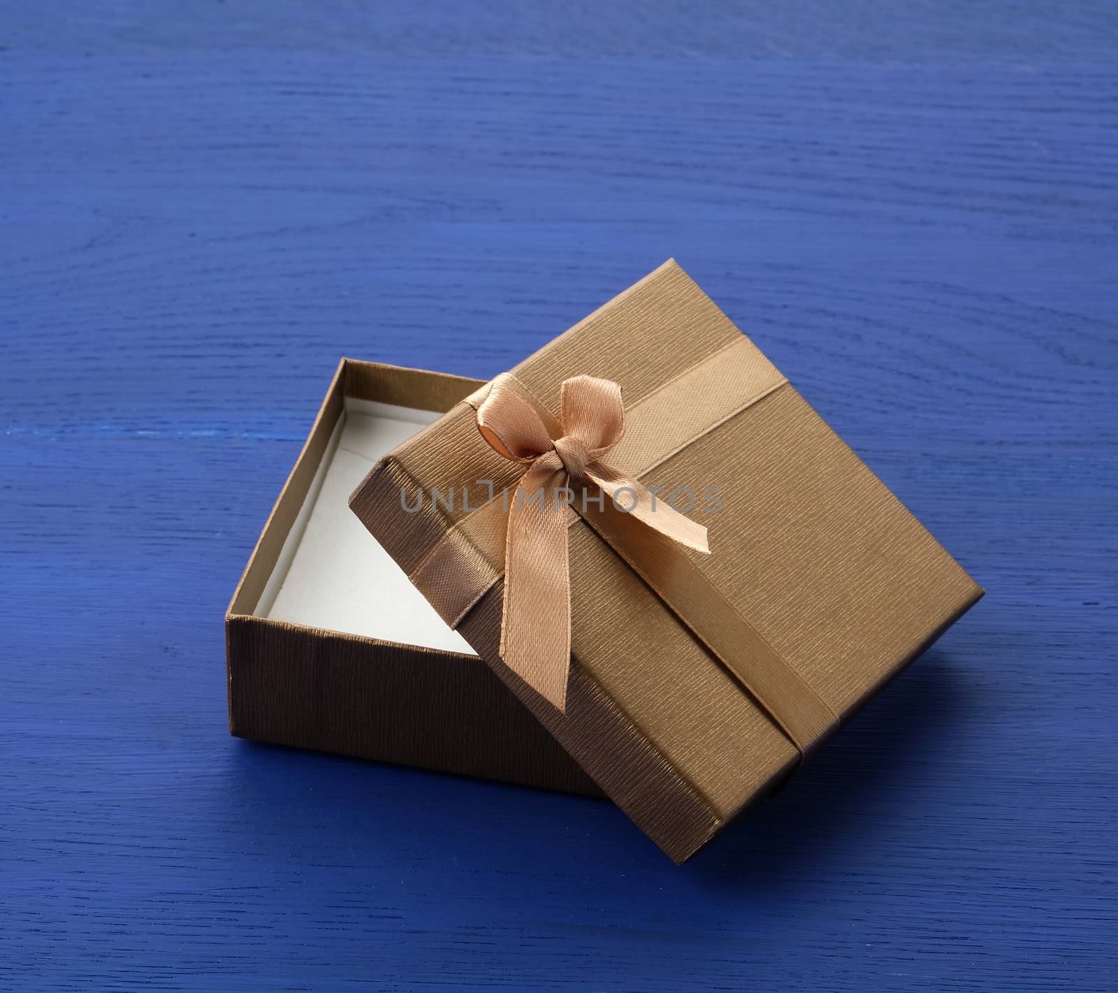 open brown square cardboard empty box, item lies on a blue wooden background, close up