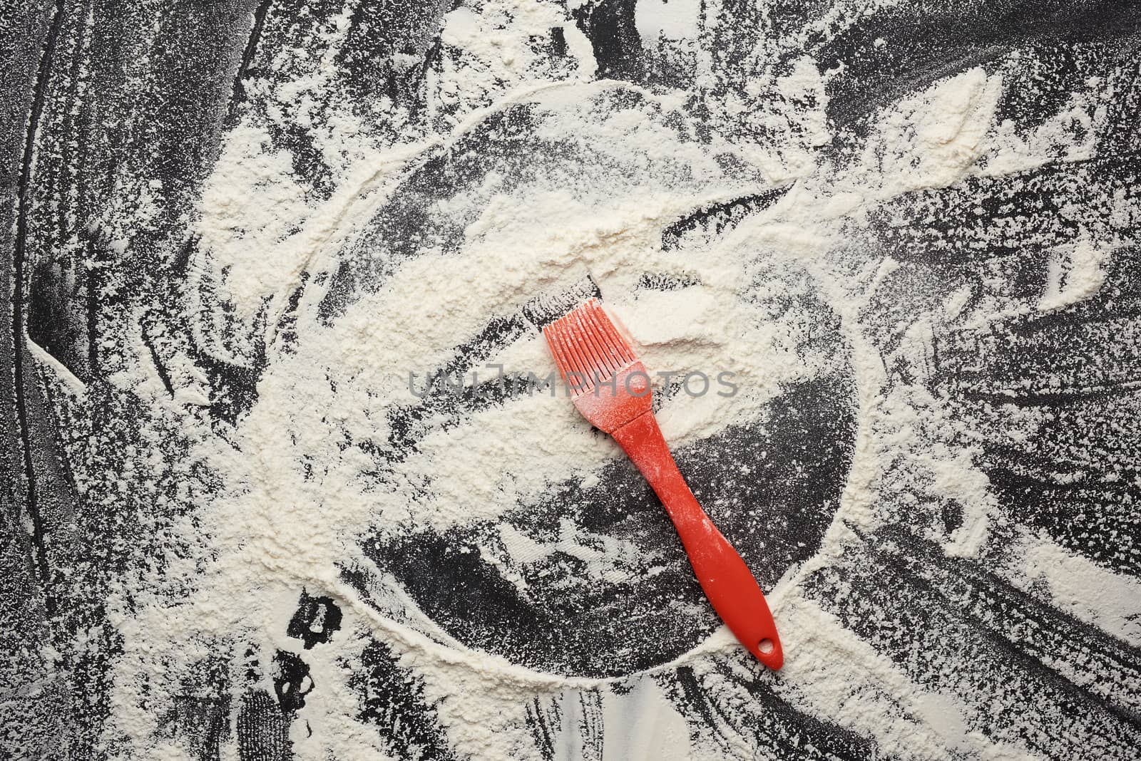 white wheat flour scattered on a black wooden table, top view, kitchen backdrop, copy space