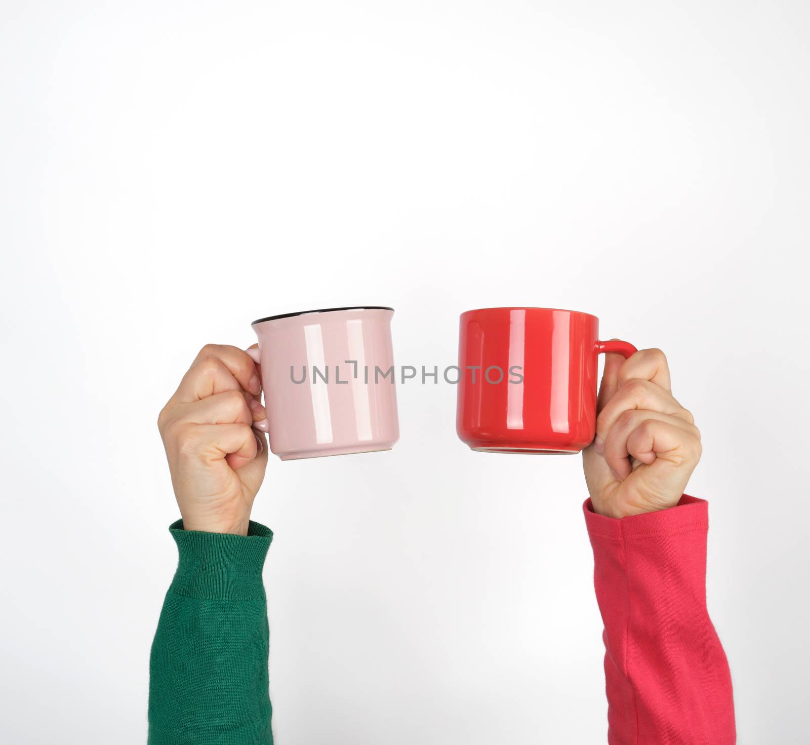 two hands holding ceramic mugs on a white background, copy space, coffee time