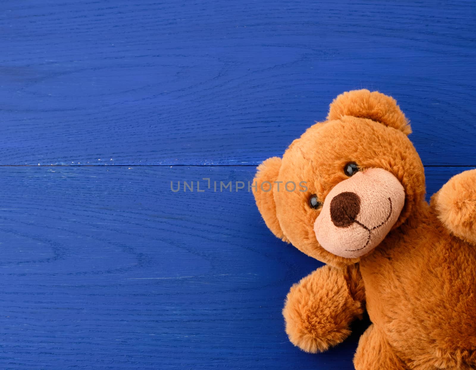 brown teddy bear on a blue wooden background, copy space