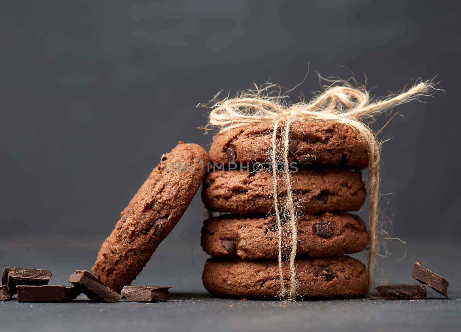 stack of round chocolate chip cookies tied with a rope on a black board, delicious dessert
