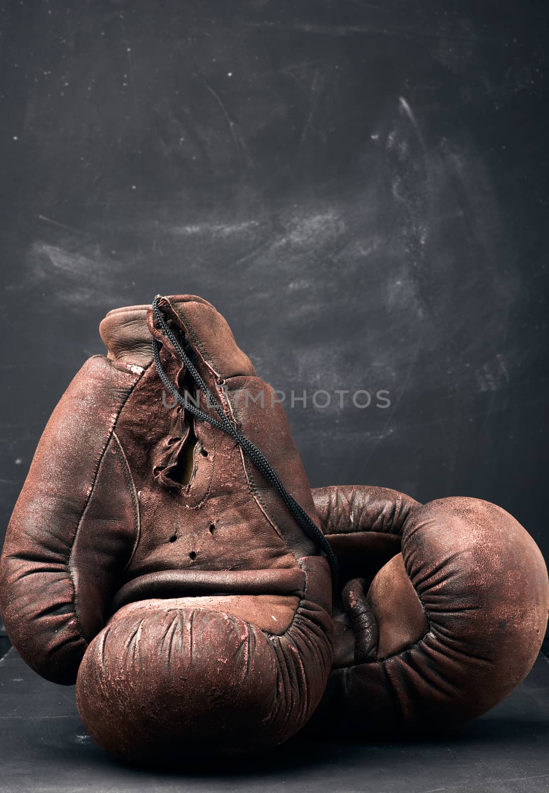 brown leather vintage boxing gloves on a black background by ndanko