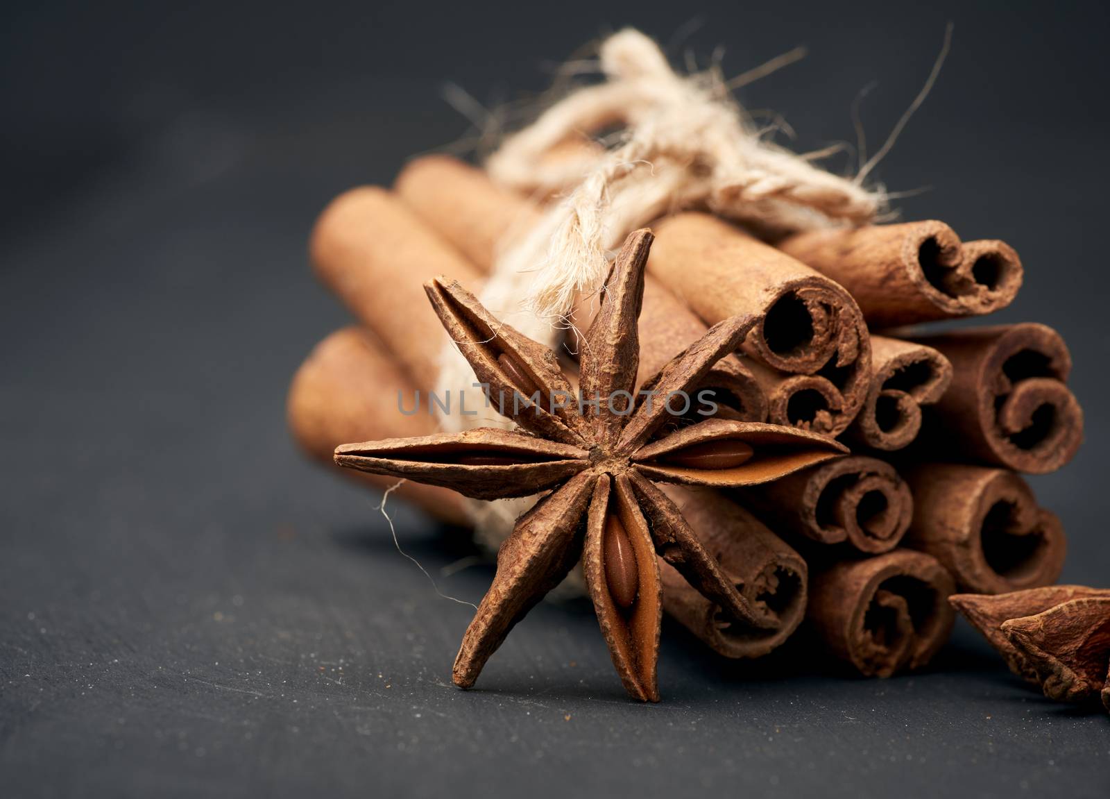 dry star anise with a bunch of brown cinnamon sticks tied with a rope, close up