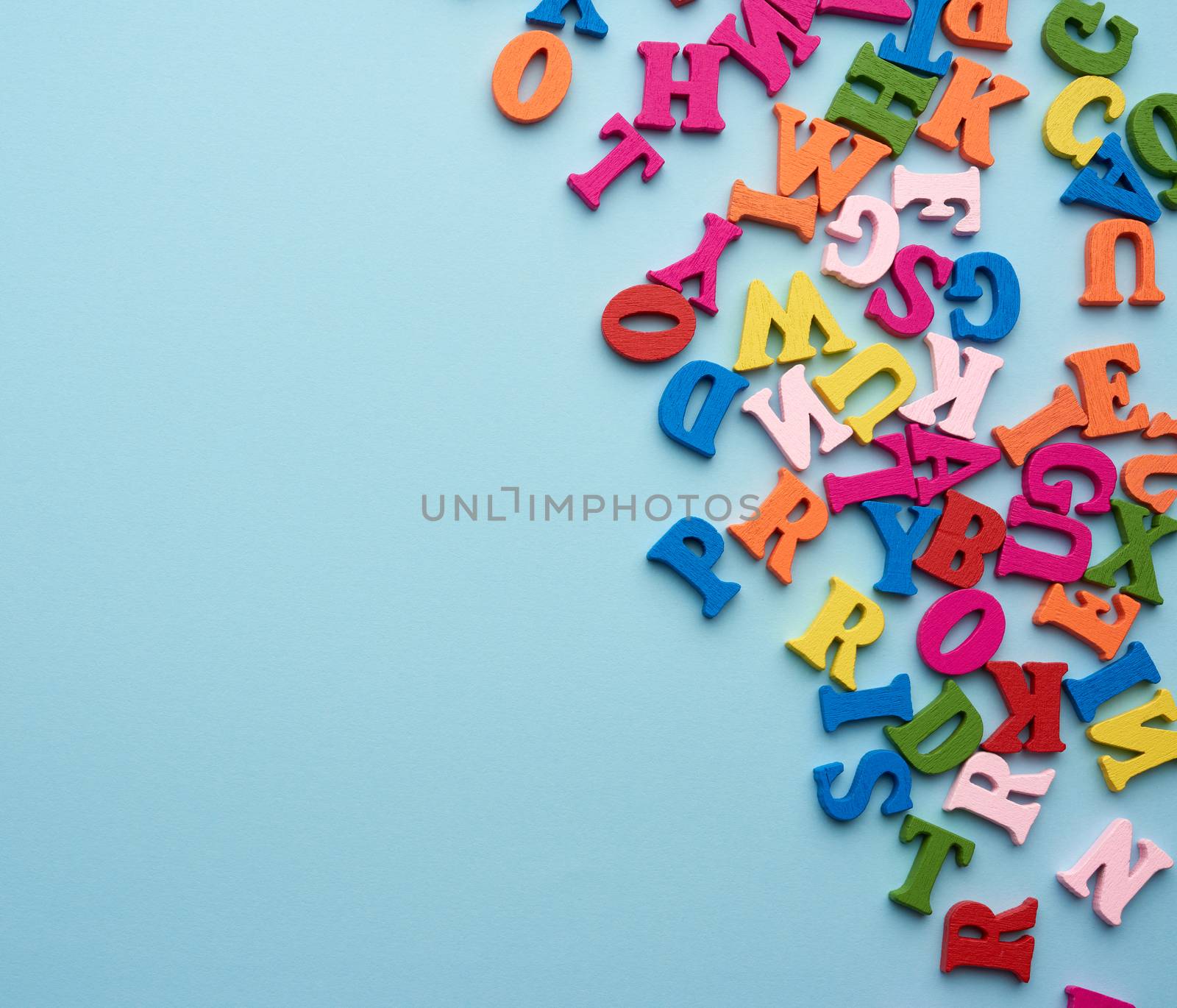 multi-colored wooden letters of the English alphabet on a blue background, top view, concept of back to school, copy space