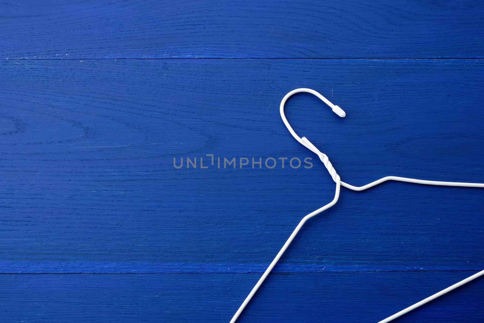 thin white metal hanger on a blue wooden background, close up