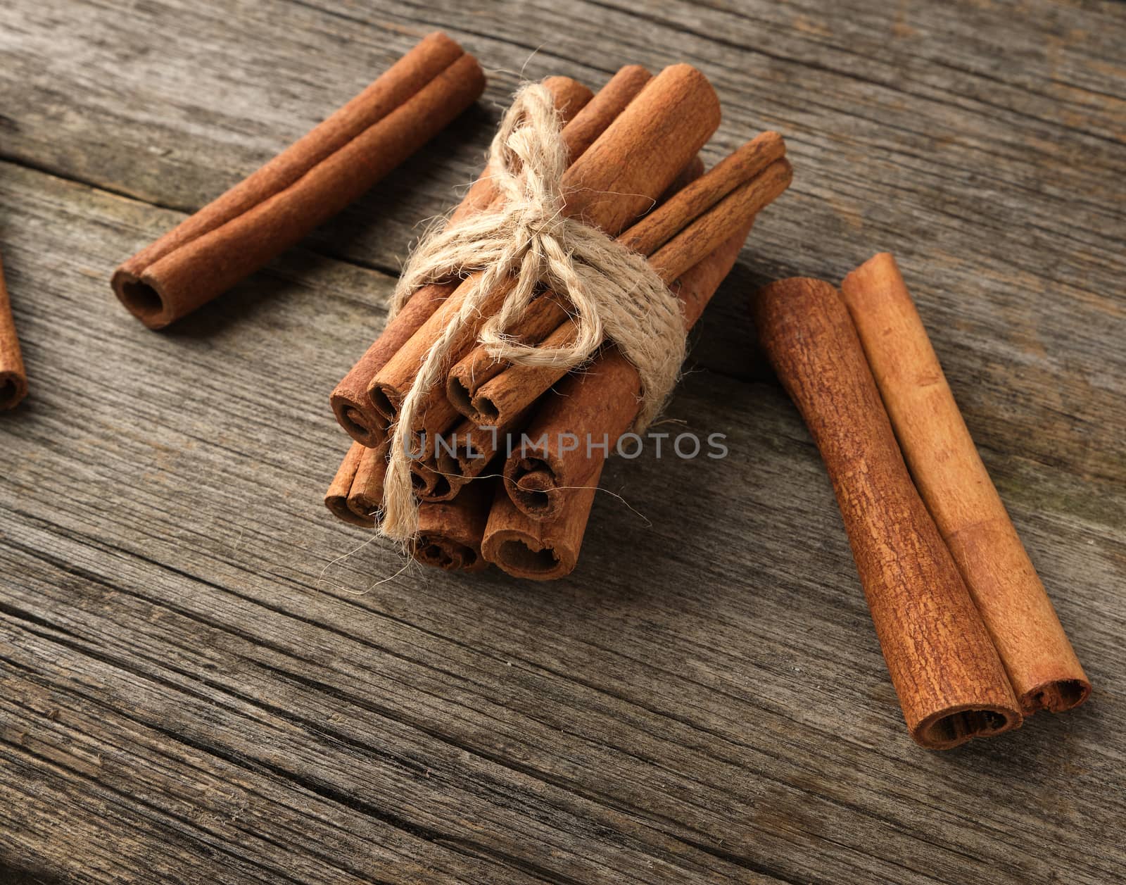 brown cinnamon sticks tied in a bun on a gray wooden background, tasty and fragrant spice, close up