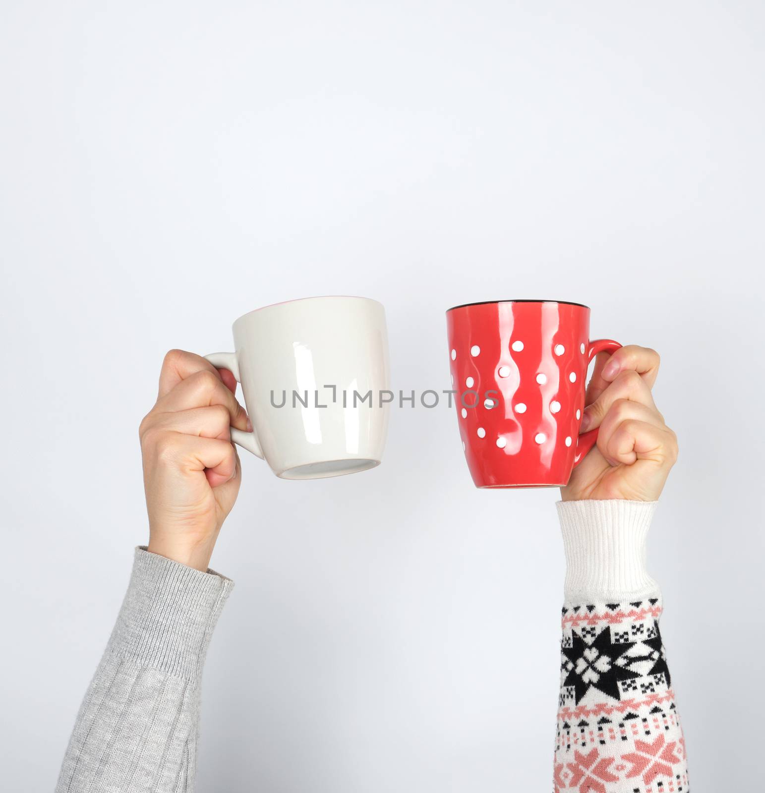 two hands holding ceramic mugs on a white background, copy space, coffee time