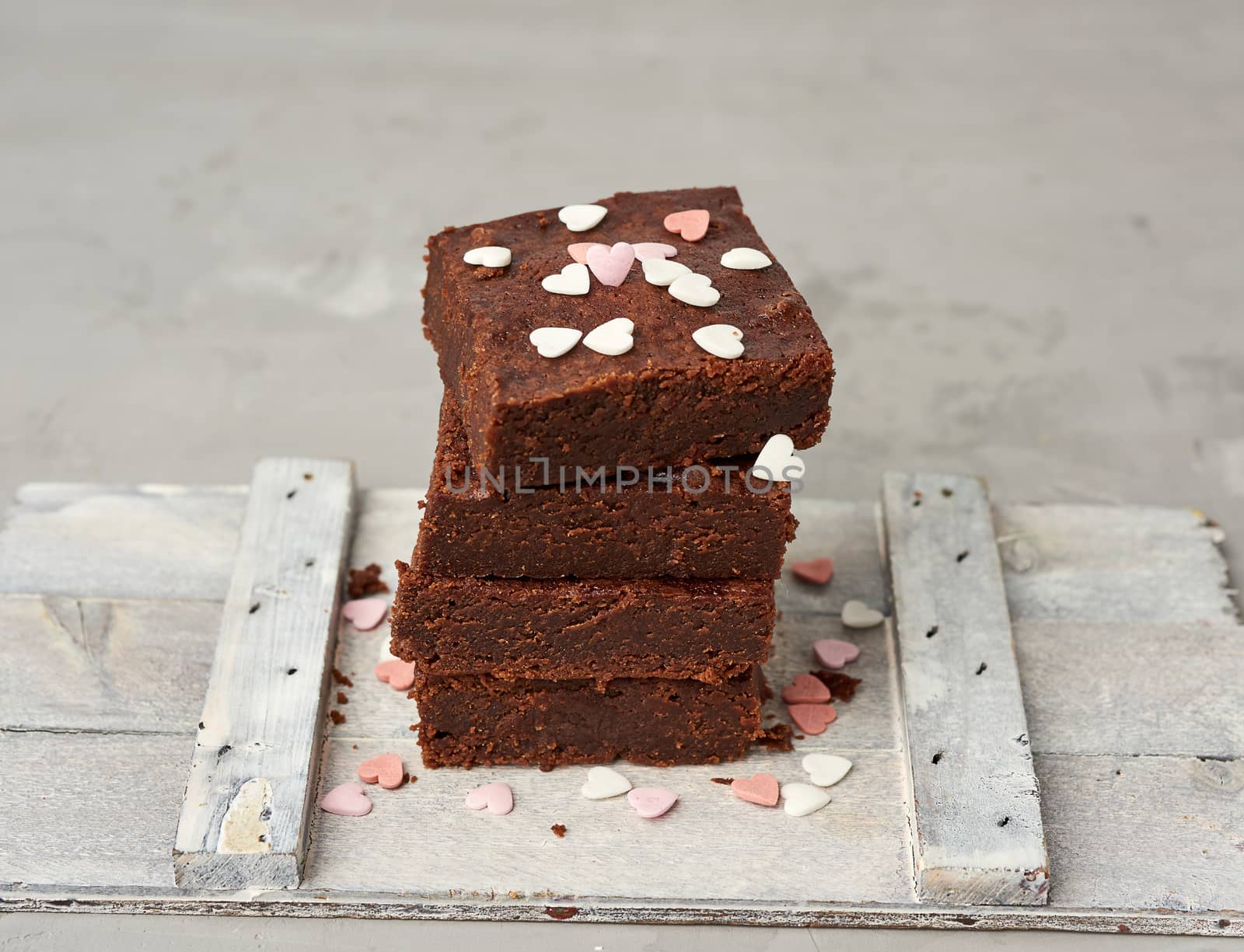 stack of square baked brownie chocolate cake slices on a white background, delicious dessert, close up