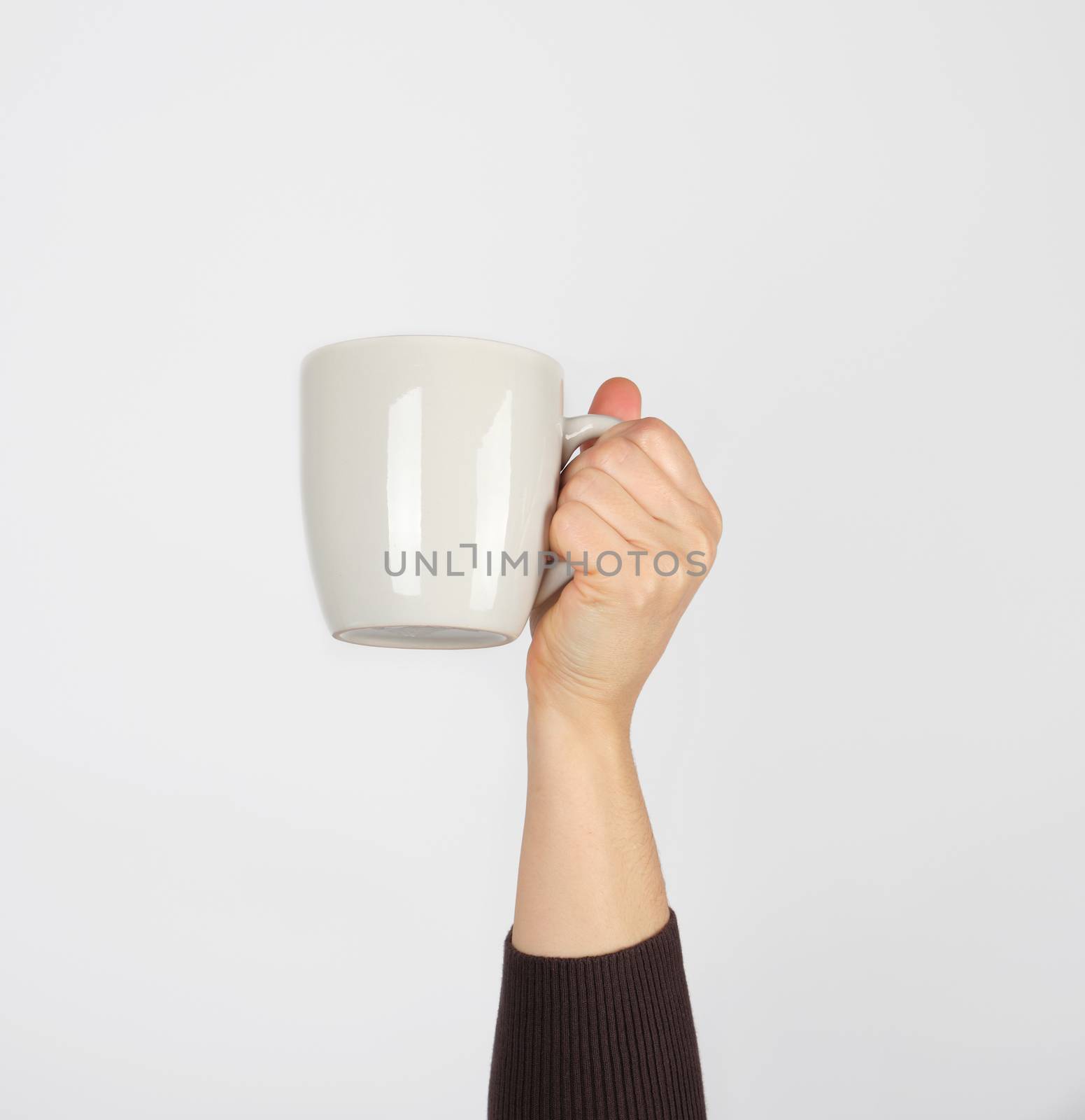 white ceramic cup in a female hand on a white background by ndanko