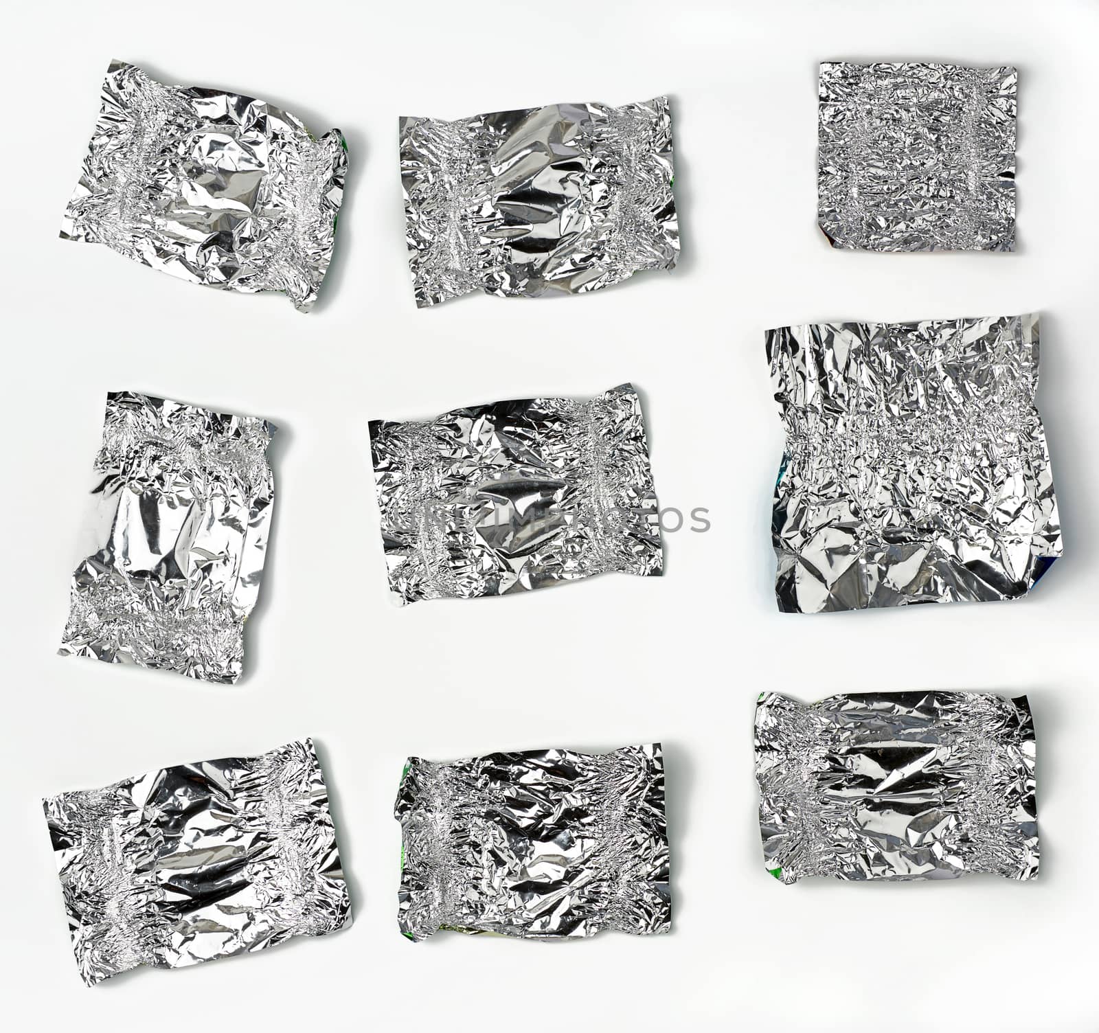 various crumpled foil used candy wrappers on a white background, top view