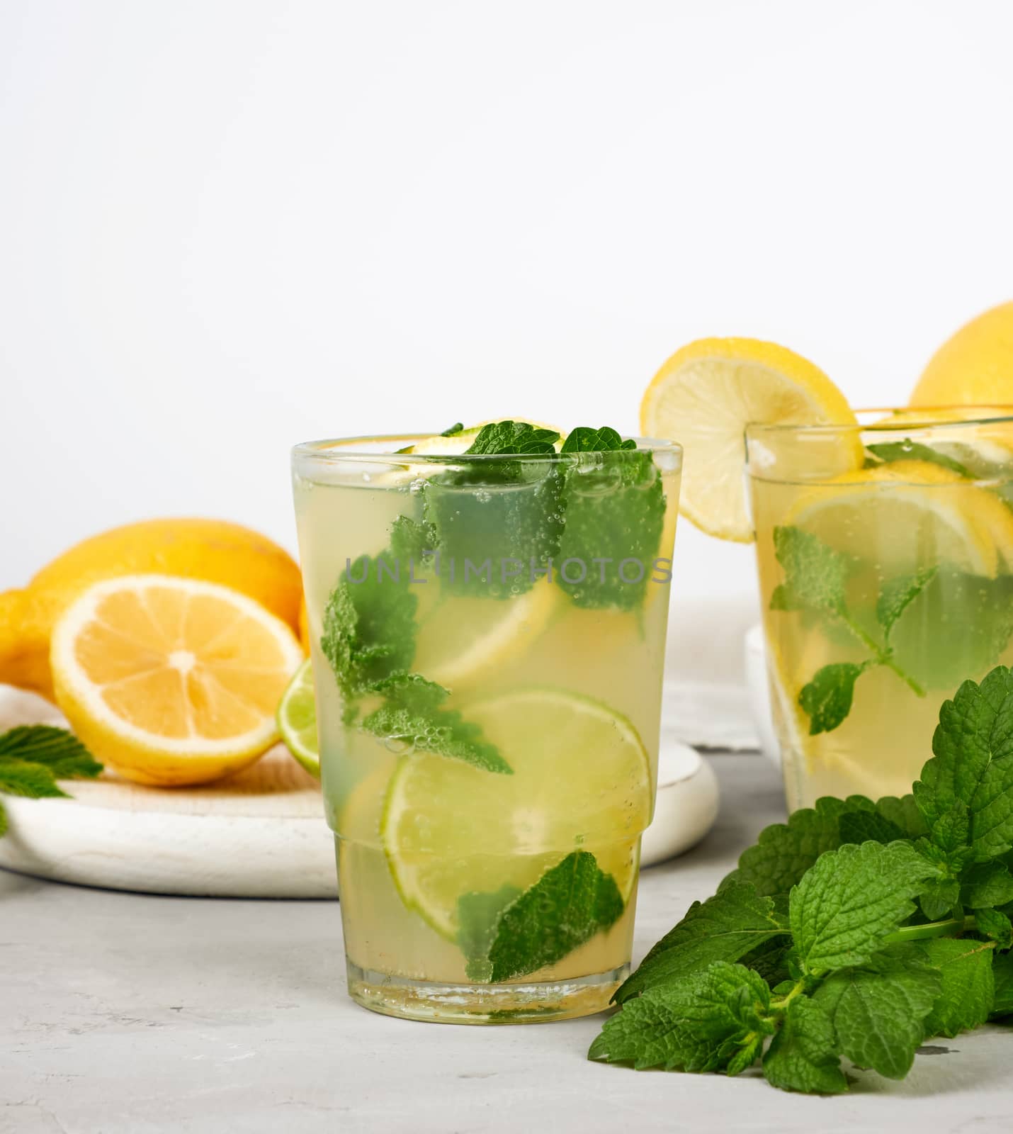summer refreshing drink lemonade with lemons, mint leaves, lime in a glass, next to the ingredients for making a cocktail