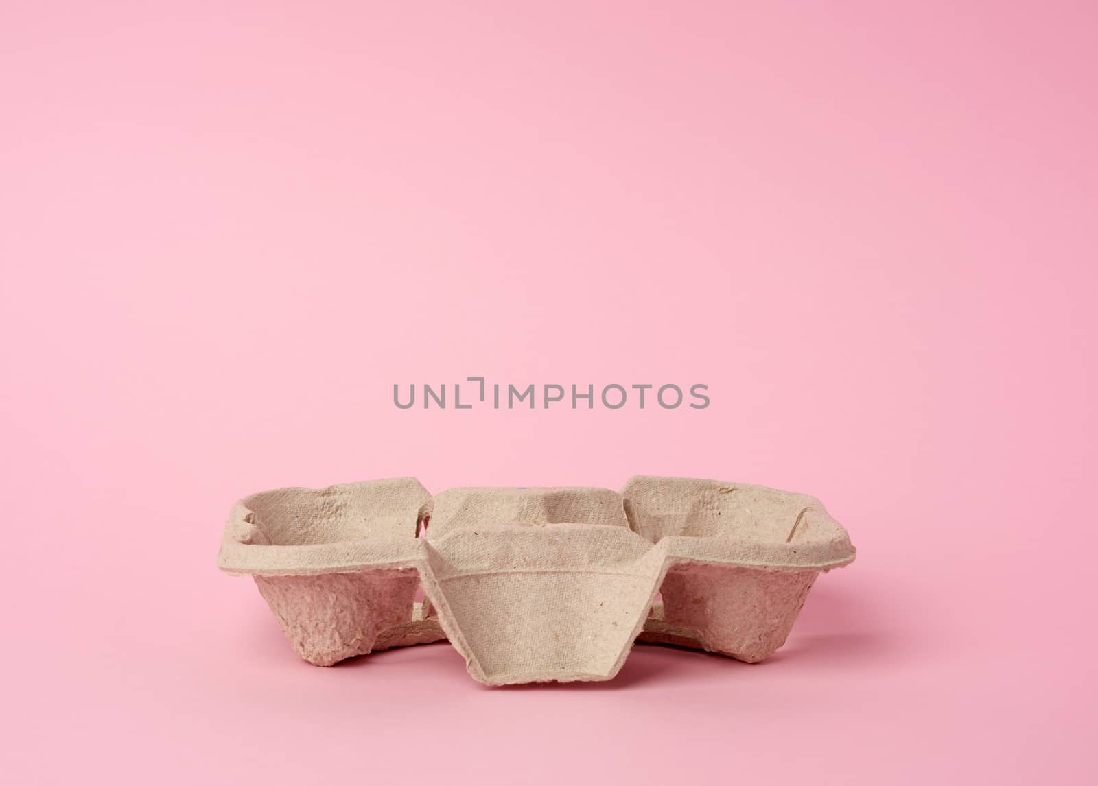 cardboard recycle stand for hot drinks for two cups is on a pink background, close up