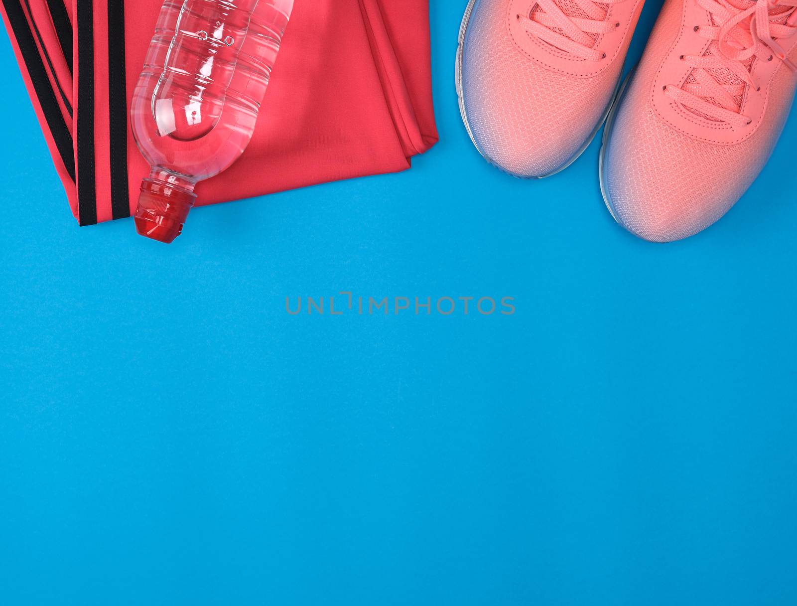 sport textile shoes and other items for fitness on a blue background, top view, copy space