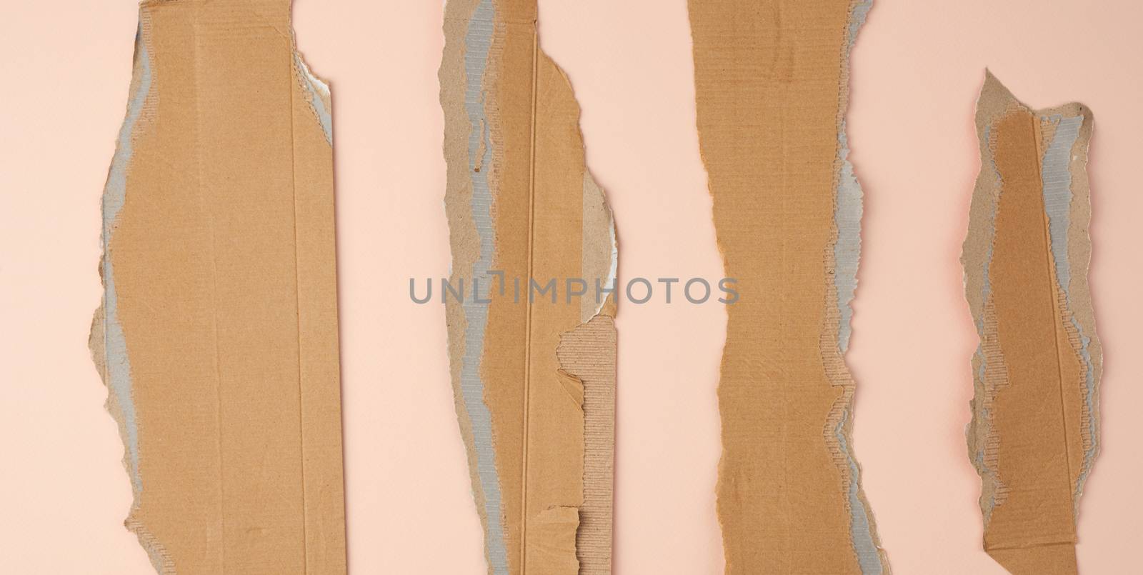 pieces of cardboard corrugated paper torn edges on a beige background, abstract backdrop. Ripped paper texture.